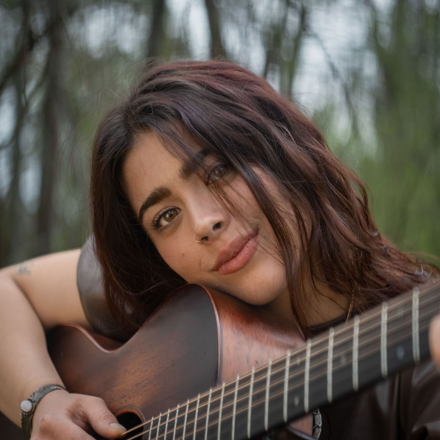 Intimate portraits with acoustic guitar against natural woodland backdrop.