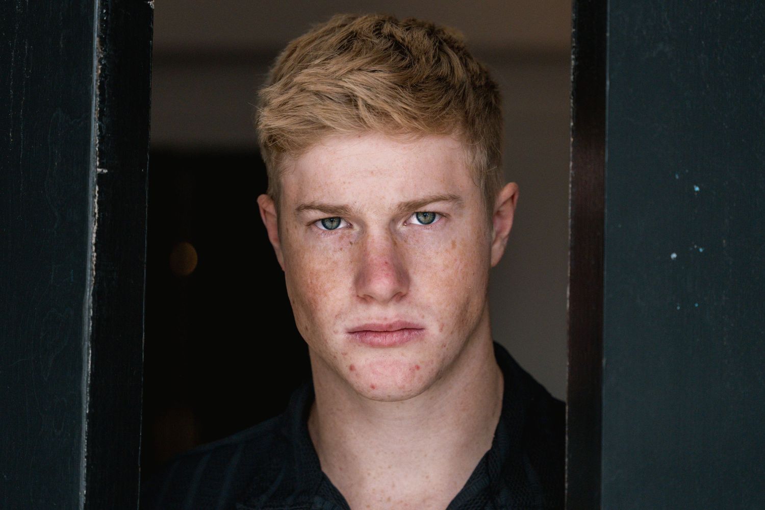 Headshot portrait against dark background with natural lighting.