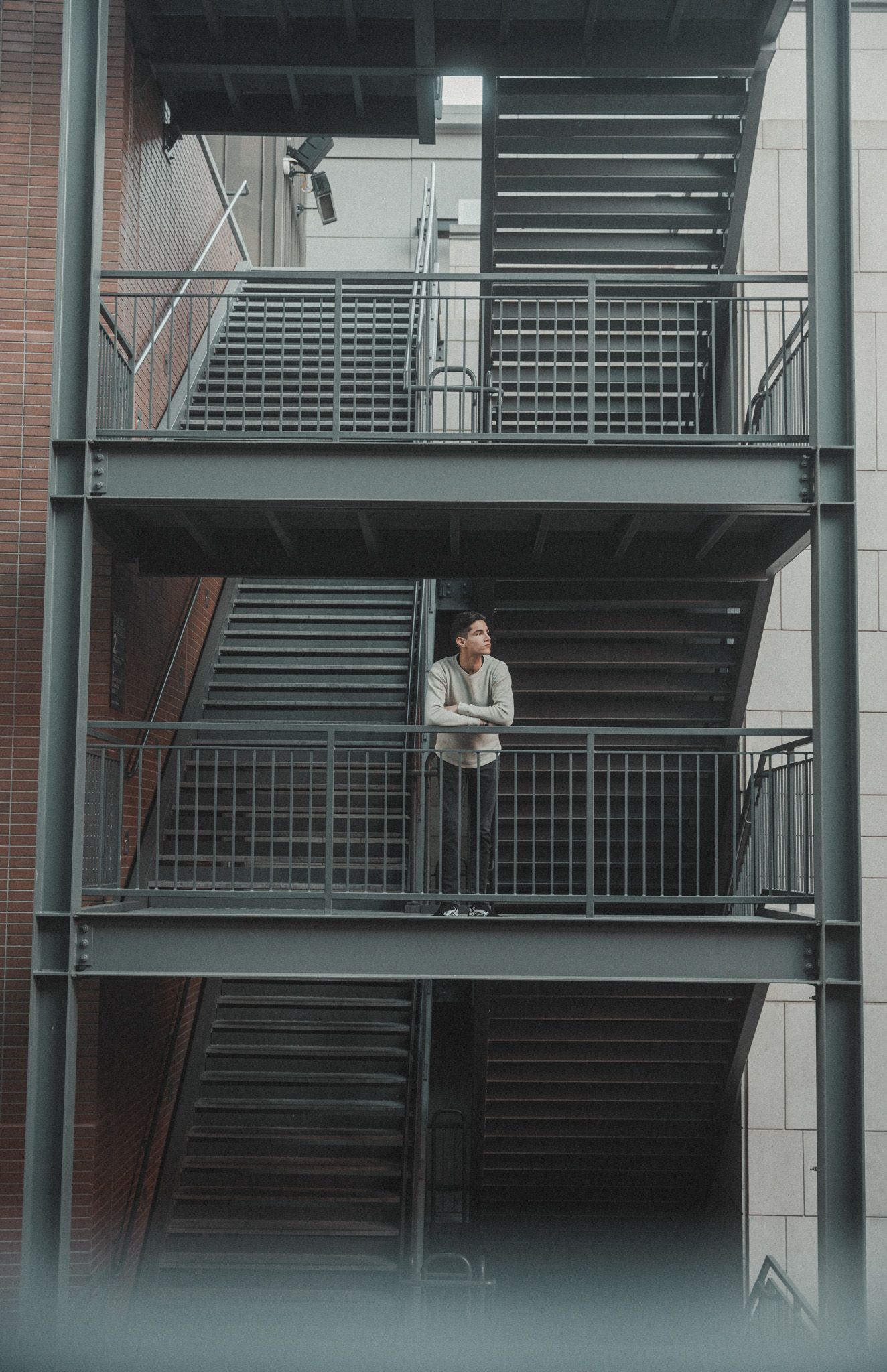 Minimalist architectural photo of a person standing alone on an industrial balcony.