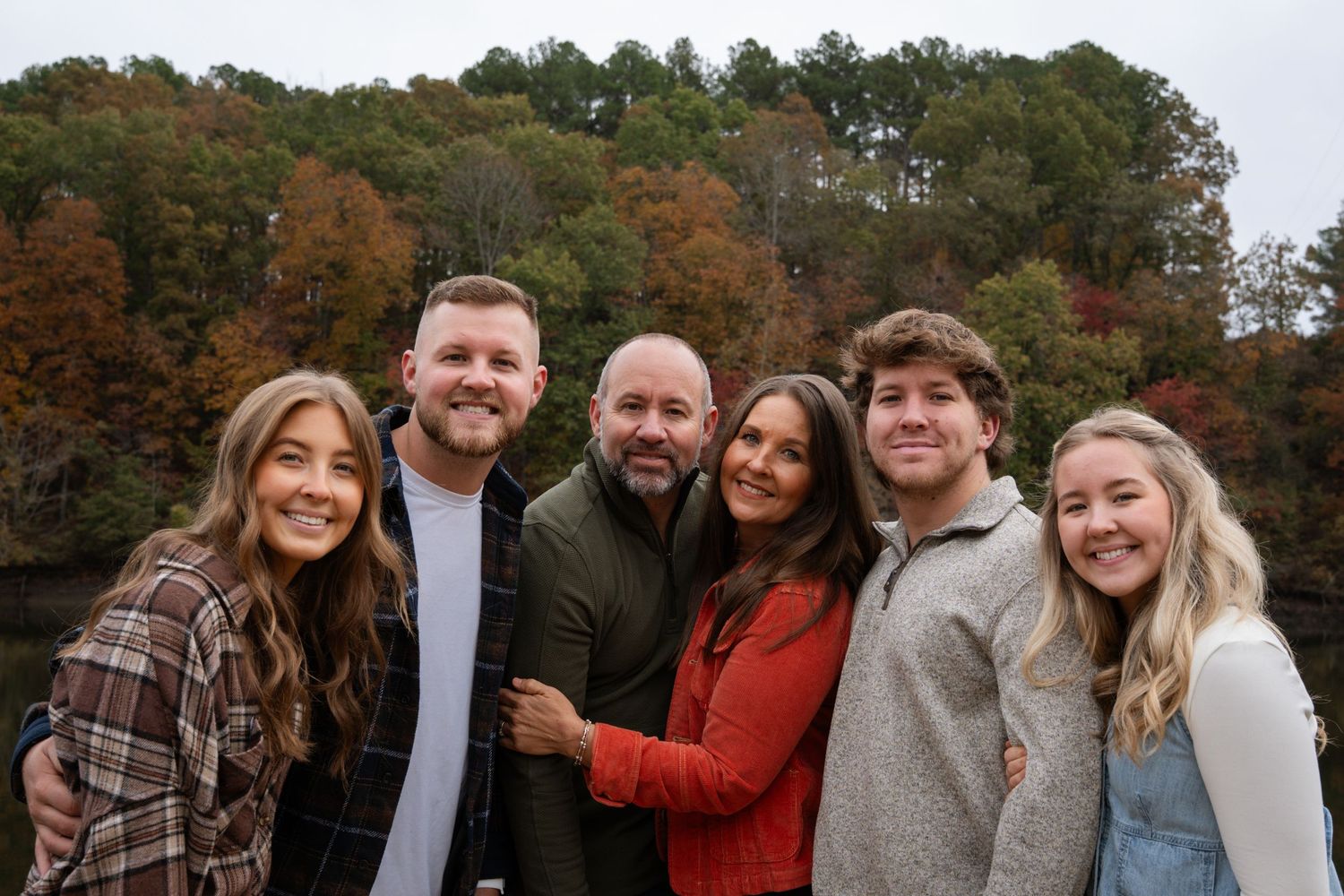 Group of friends in autumn clothing posing together outdoors during fall season.