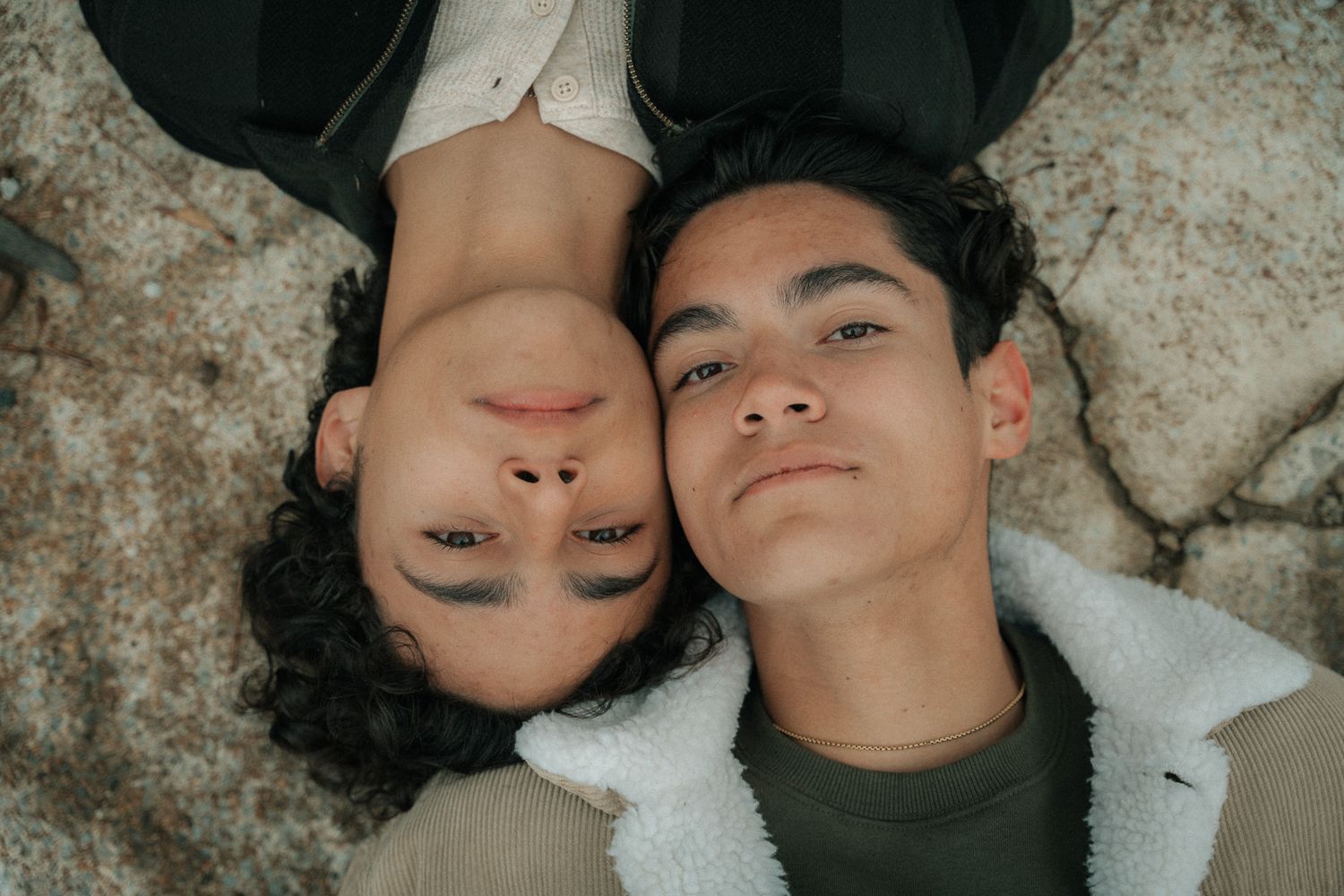 Intimate artistic photo series showing couple lying on textured ground.