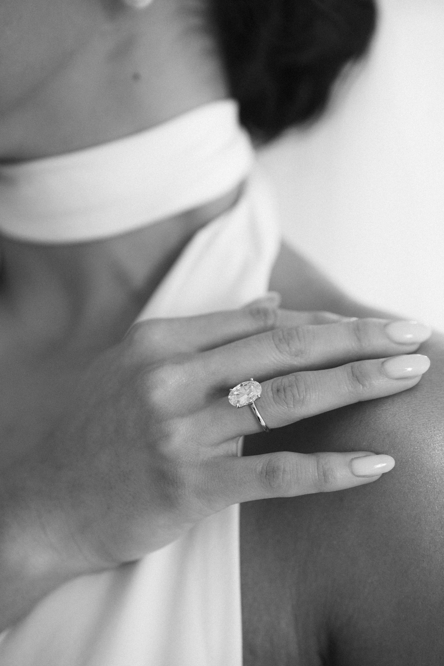 Close-up black and white photo of bride wearing large oval diamond engagement ring.