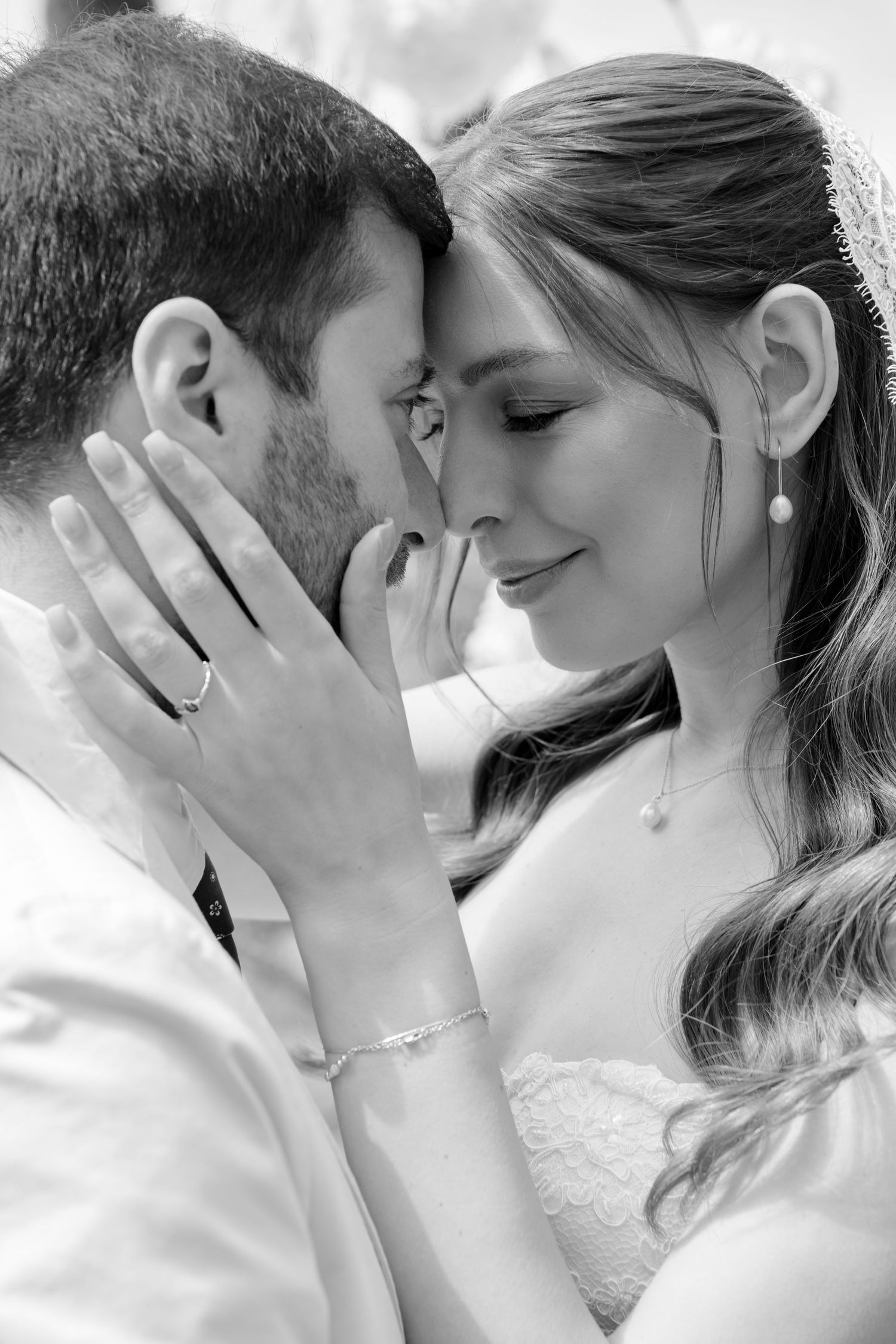 Intimate black and white portrait of bride and groom touching foreheads tenderly on wedding day.