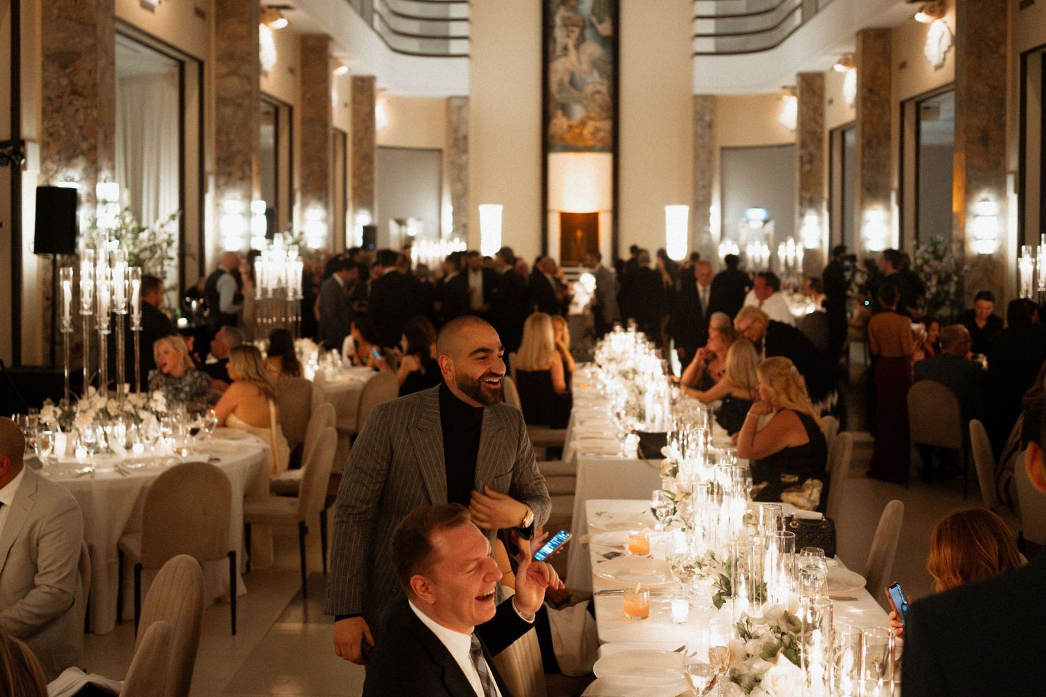 Elegant wedding reception venue with crystal chandeliers and candlelit tables set for a formal dinner celebration.