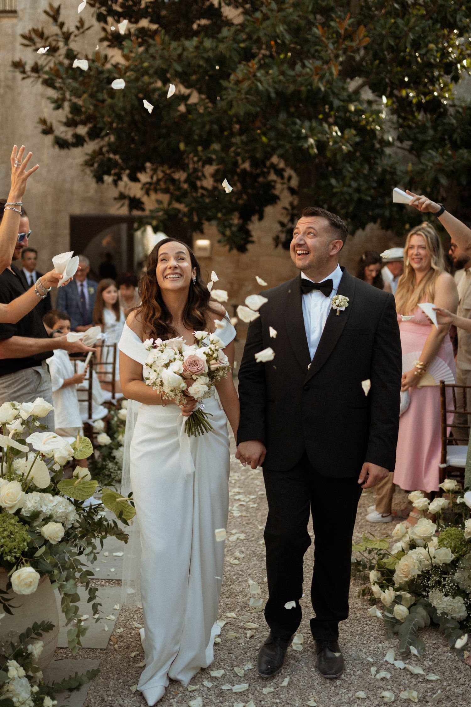 Wedding party members in formal attire celebrate joyfully while walking together outdoors.