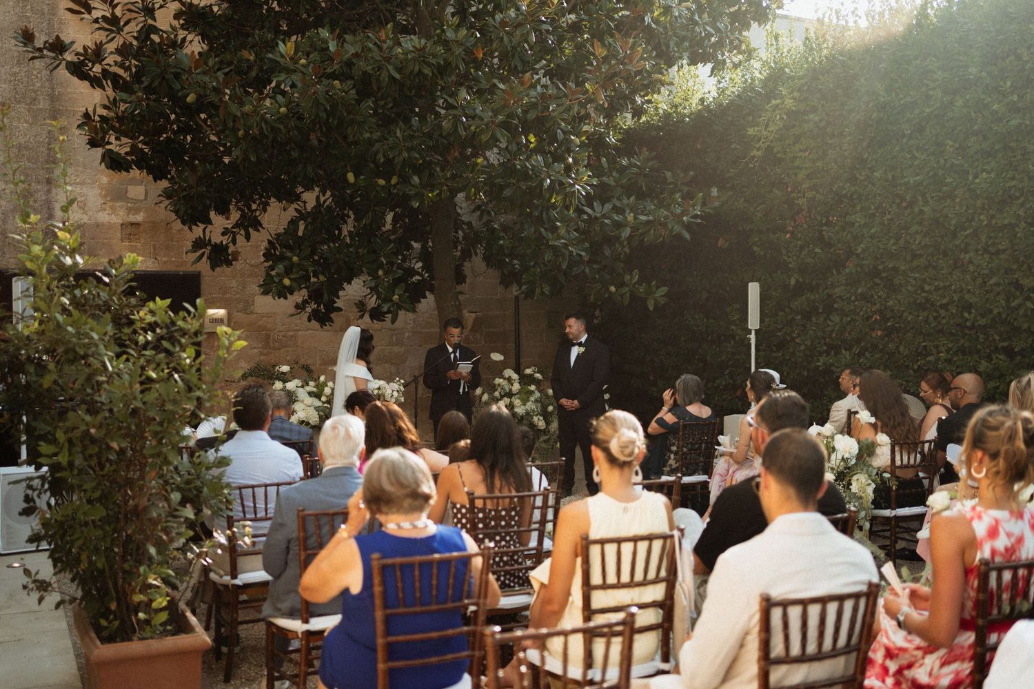 Outdoor wedding reception setup with chairs and tables under natural sunlight.