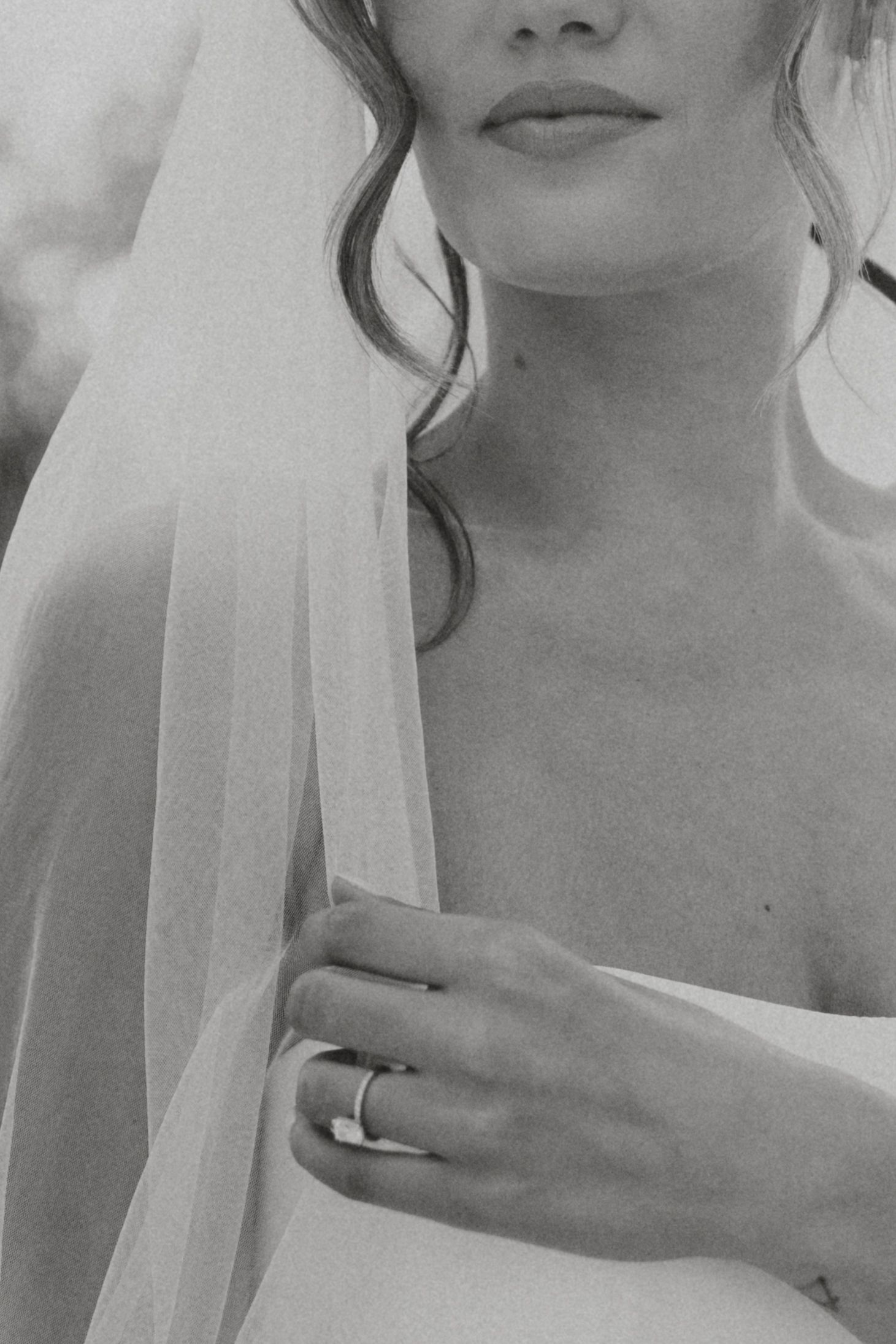 Close-up black and white detail of bridal veil and wedding ring.