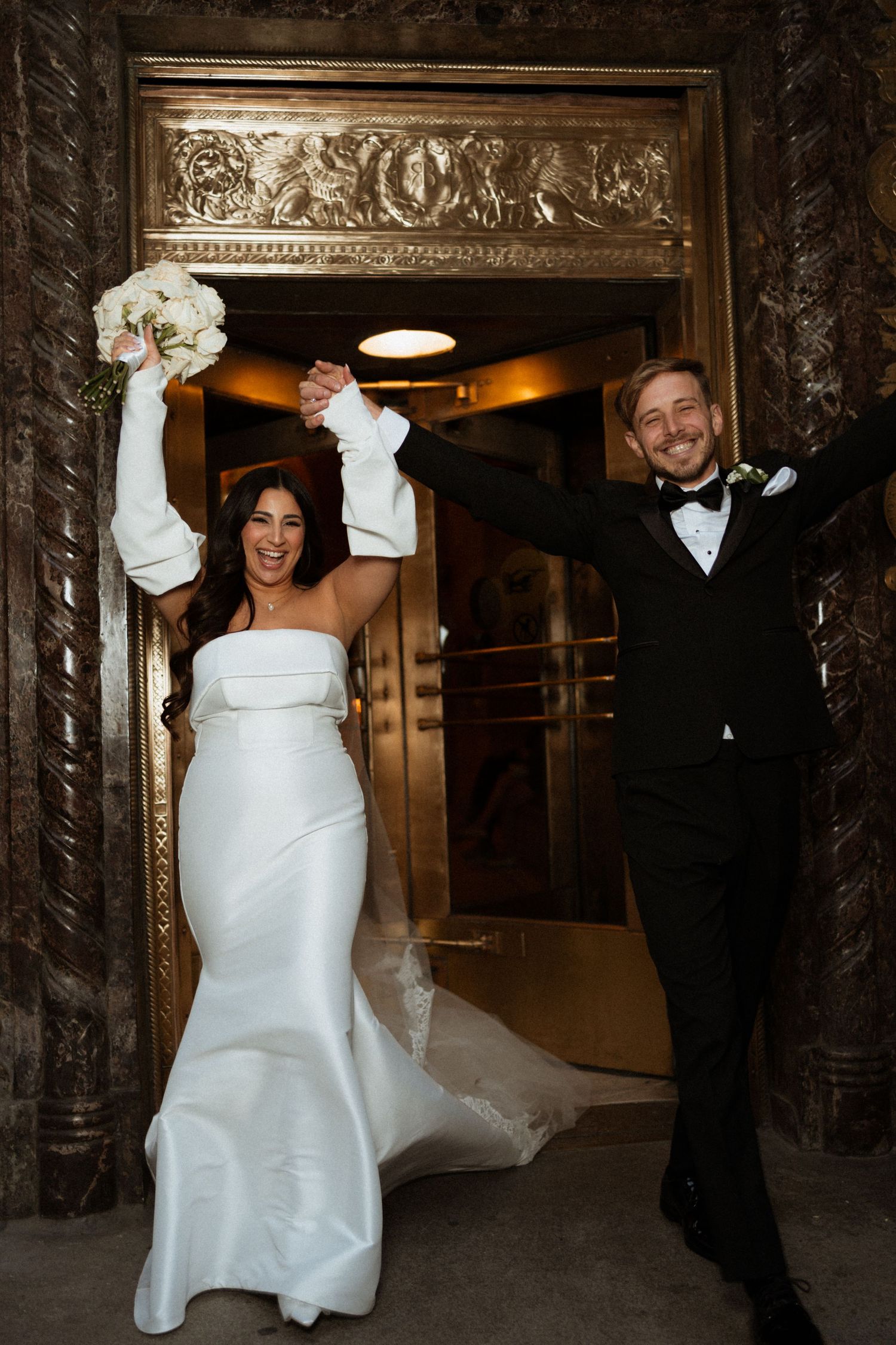 Wedding couple dancing and twirling in an elegant marble-columned hallway.