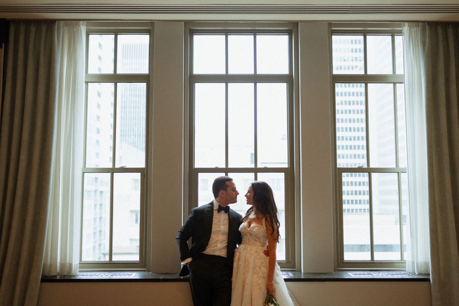 A couple stands in silhouette against bright windows in a modern office building interior.