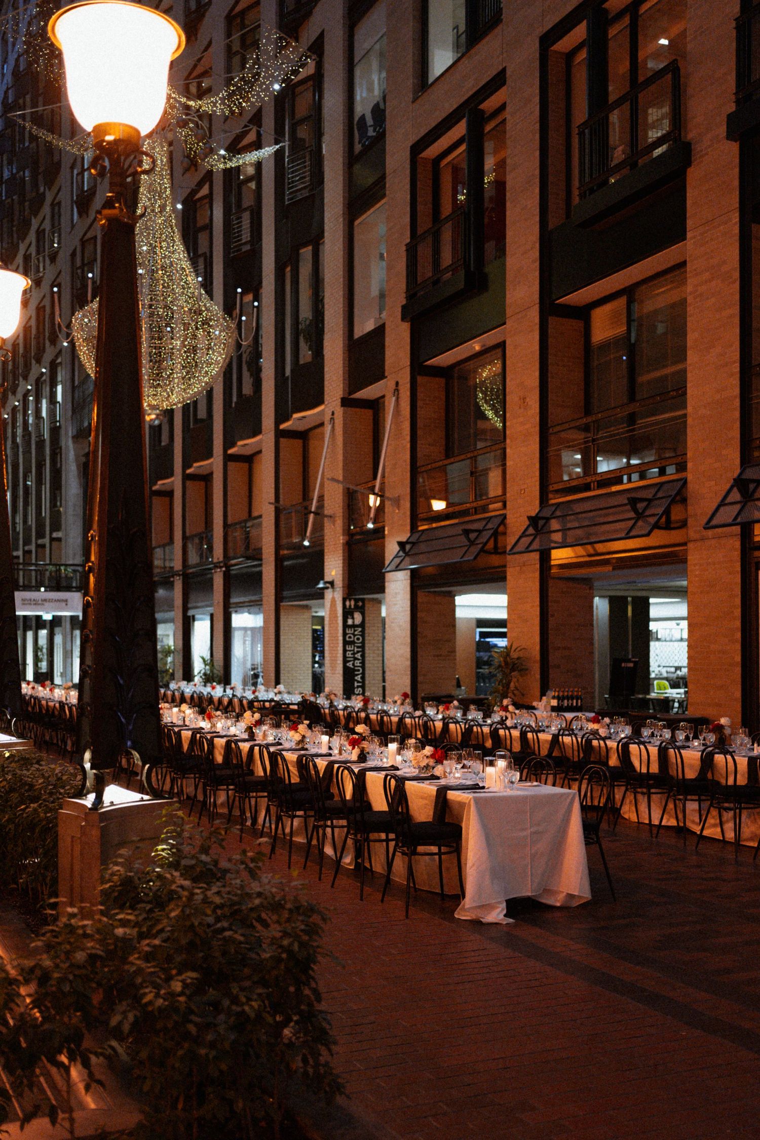 Elegant restaurant interior with rows of white-clothed tables under warm lighting and hanging crescent moon decorations.