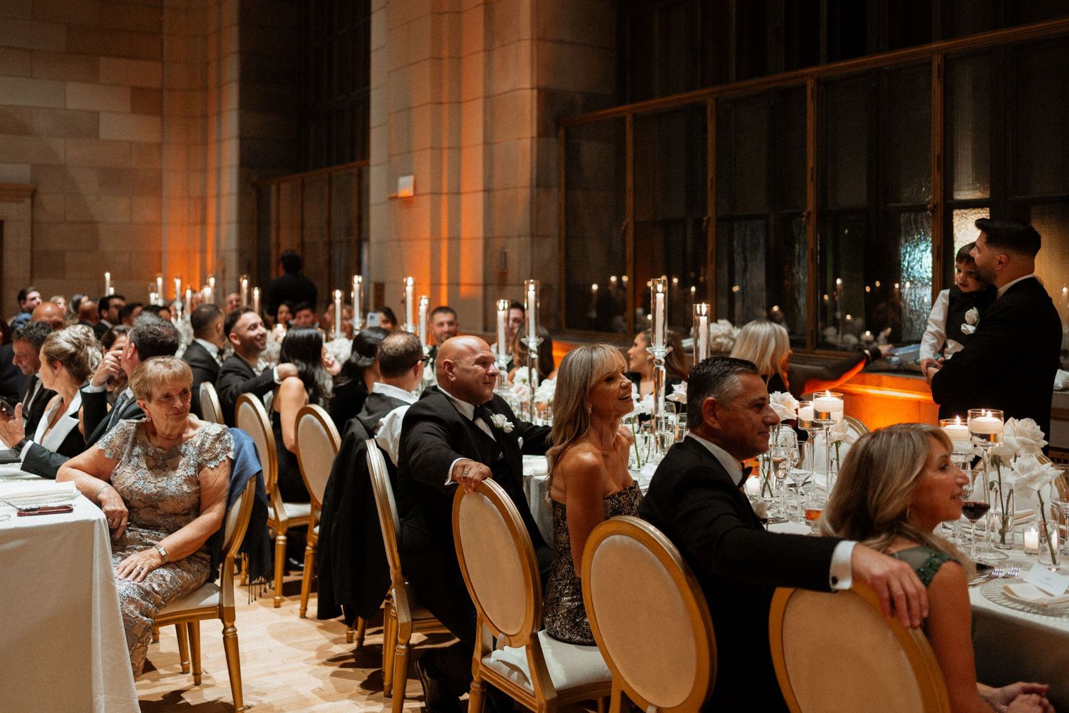 A panoramic view of guests dining in an elegant restaurant with warm lighting and upscale decor.