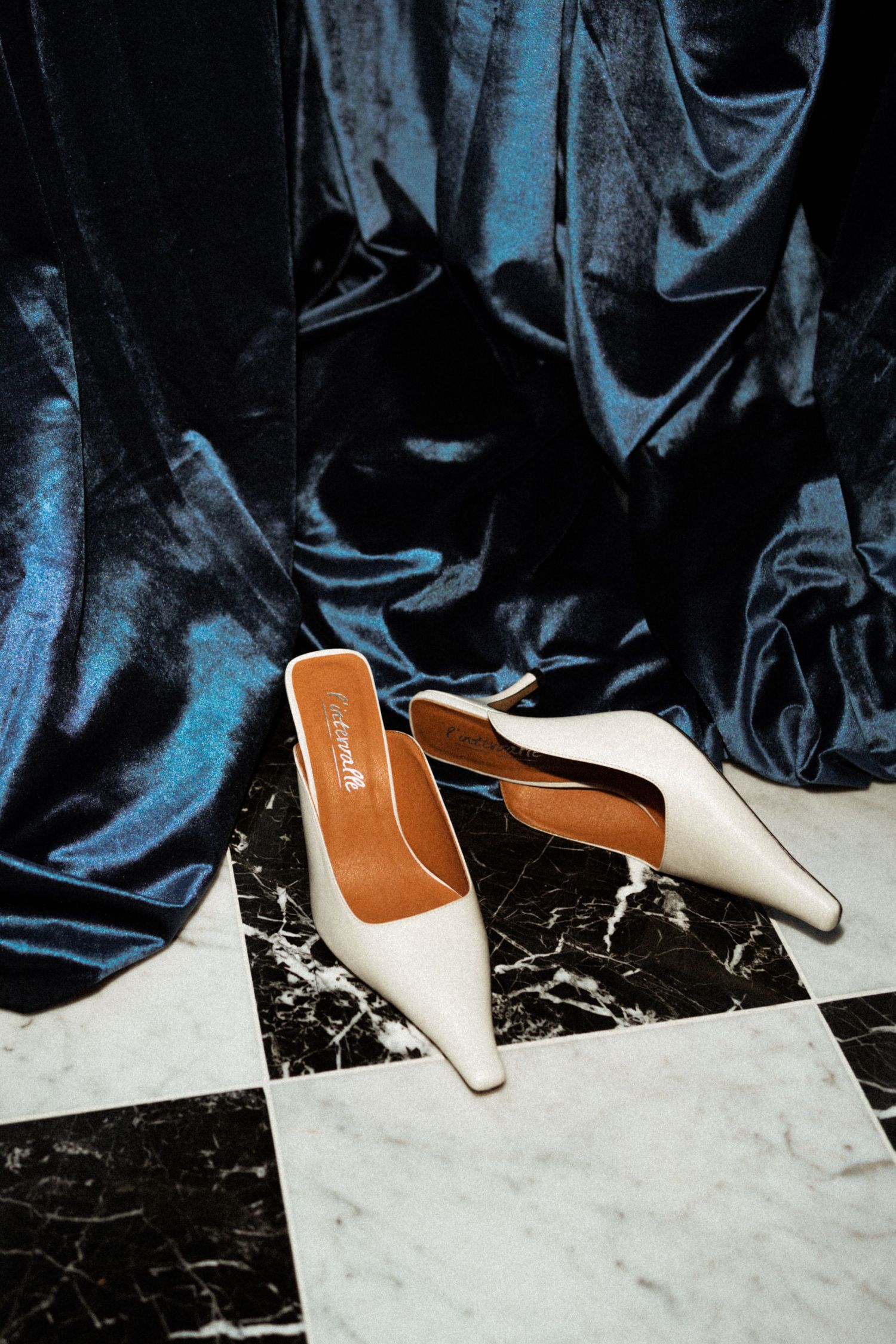 Close-up view of elegant wedding shoes on a black and white marble floor.