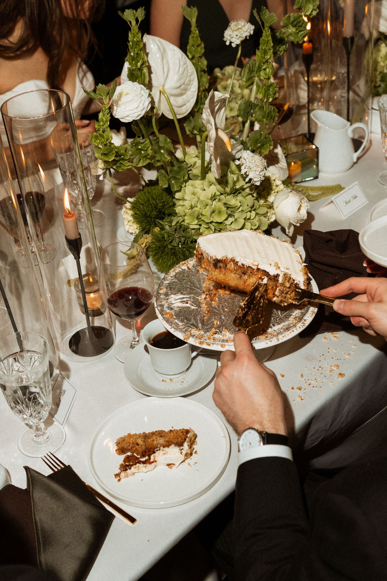 Elegant dinner table setting with wine glasses and guests enjoying dessert at a formal event.