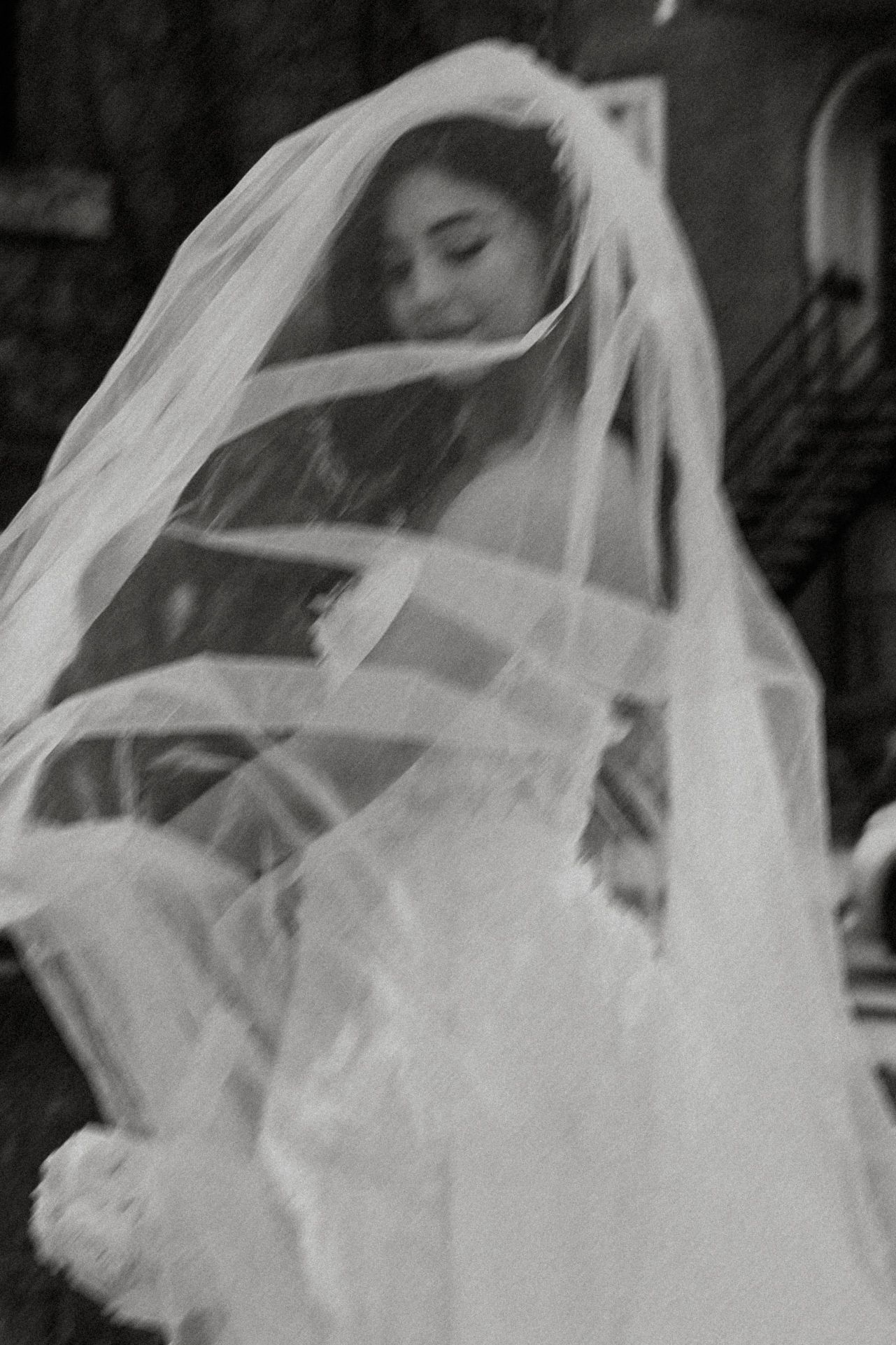 A flowing white bridal veil billows dramatically in the wind creating an ethereal silhouette against a dark background.