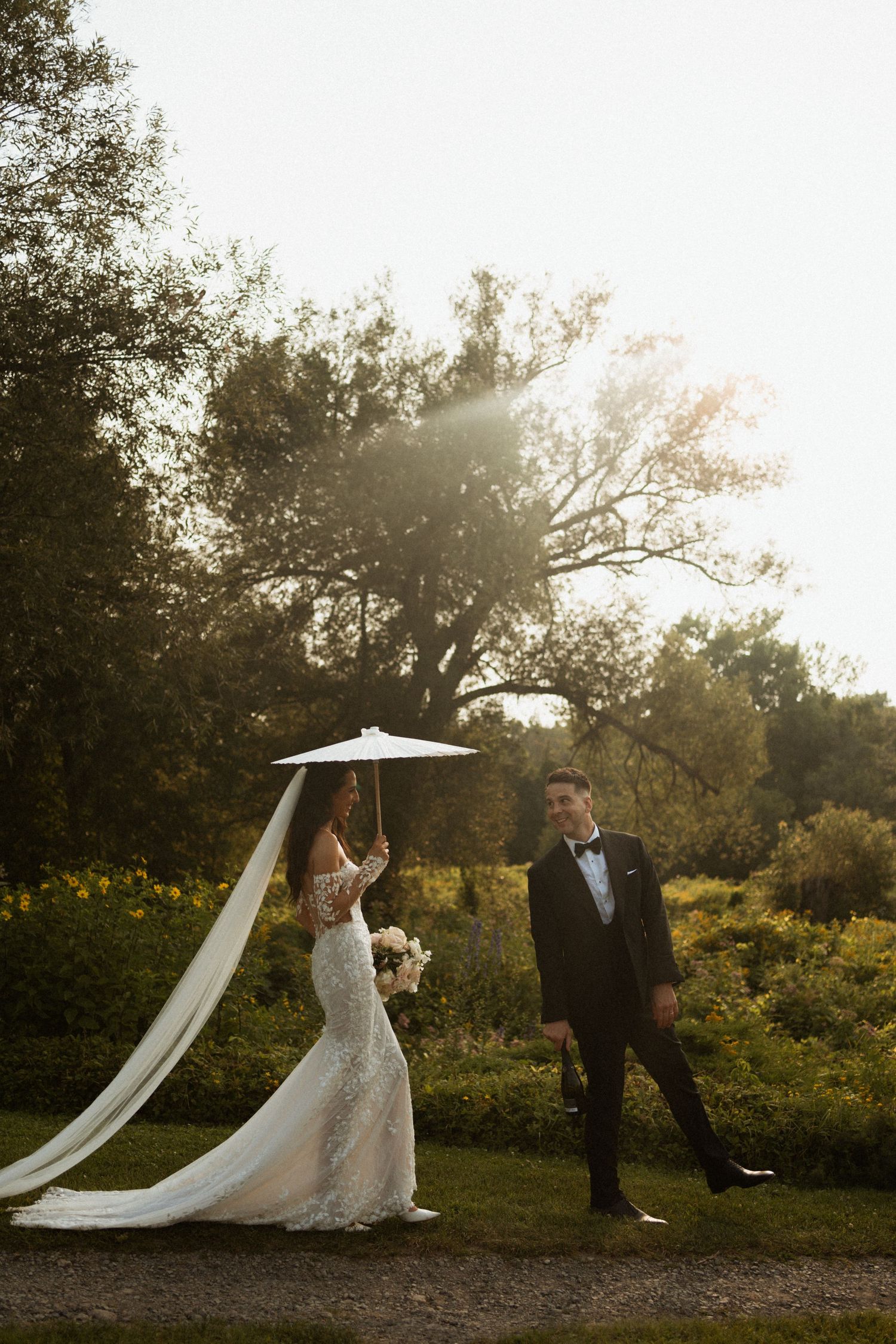 A romantic wedding photoshoot in a sunlit garden with flowing veil catching the golden light.