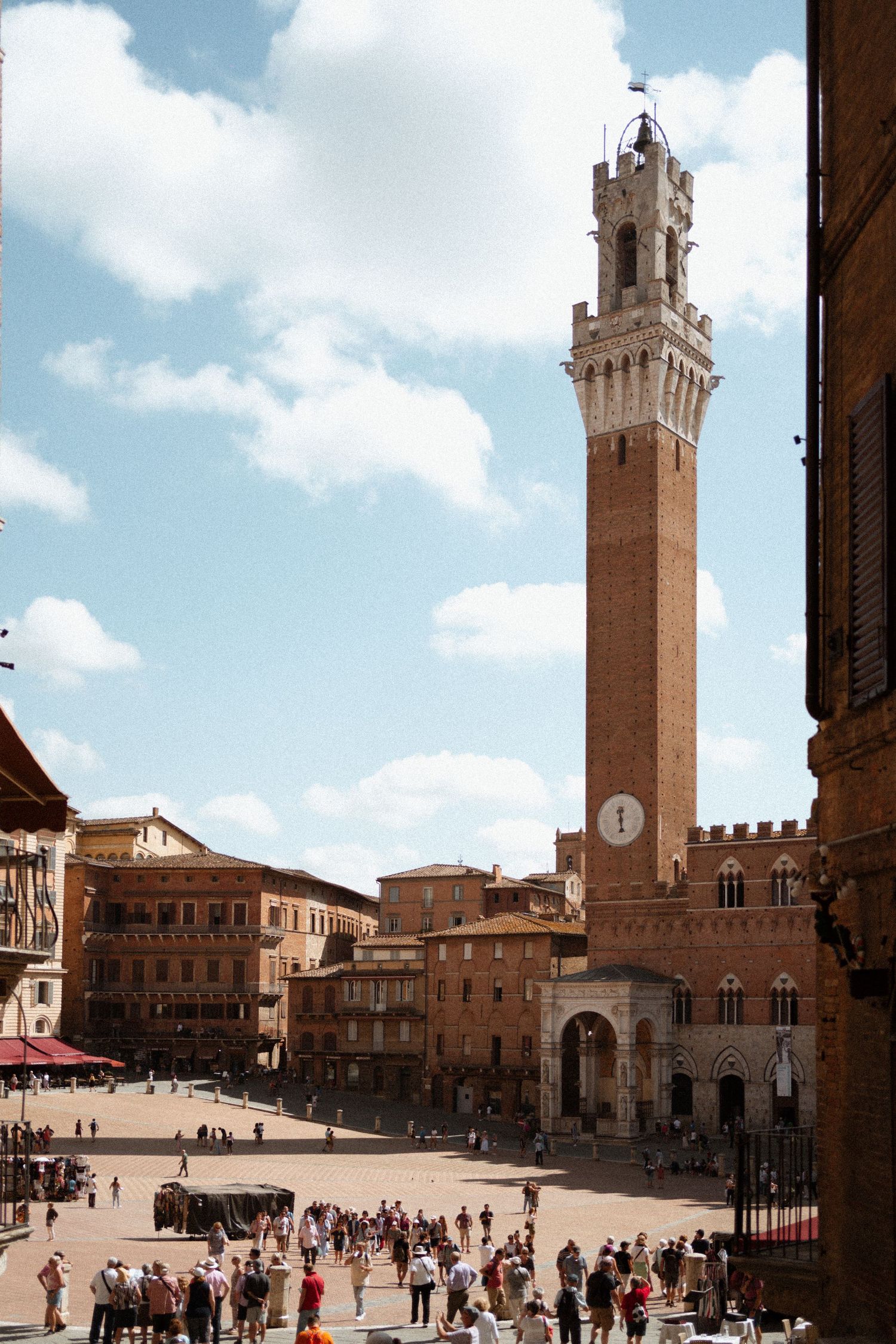 Historic Piazza del Campo in Siena, Italy with the iconic Torre del Mangia bell tower rising above medieval buildings.
