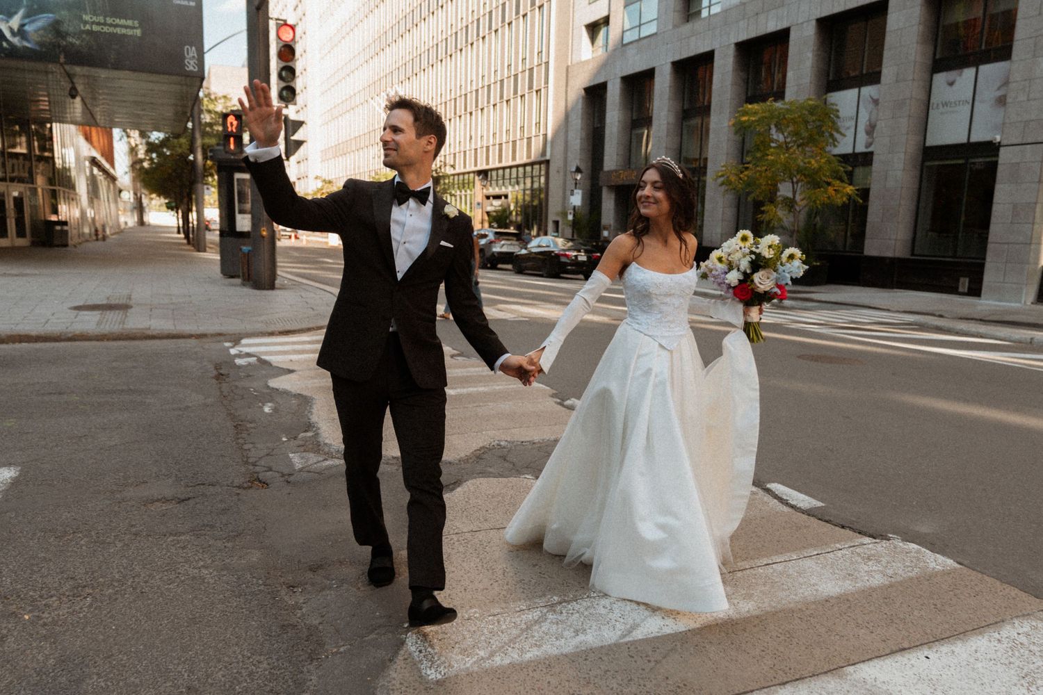 A bride and groom walk together on a city street during their wedding photoshoot.