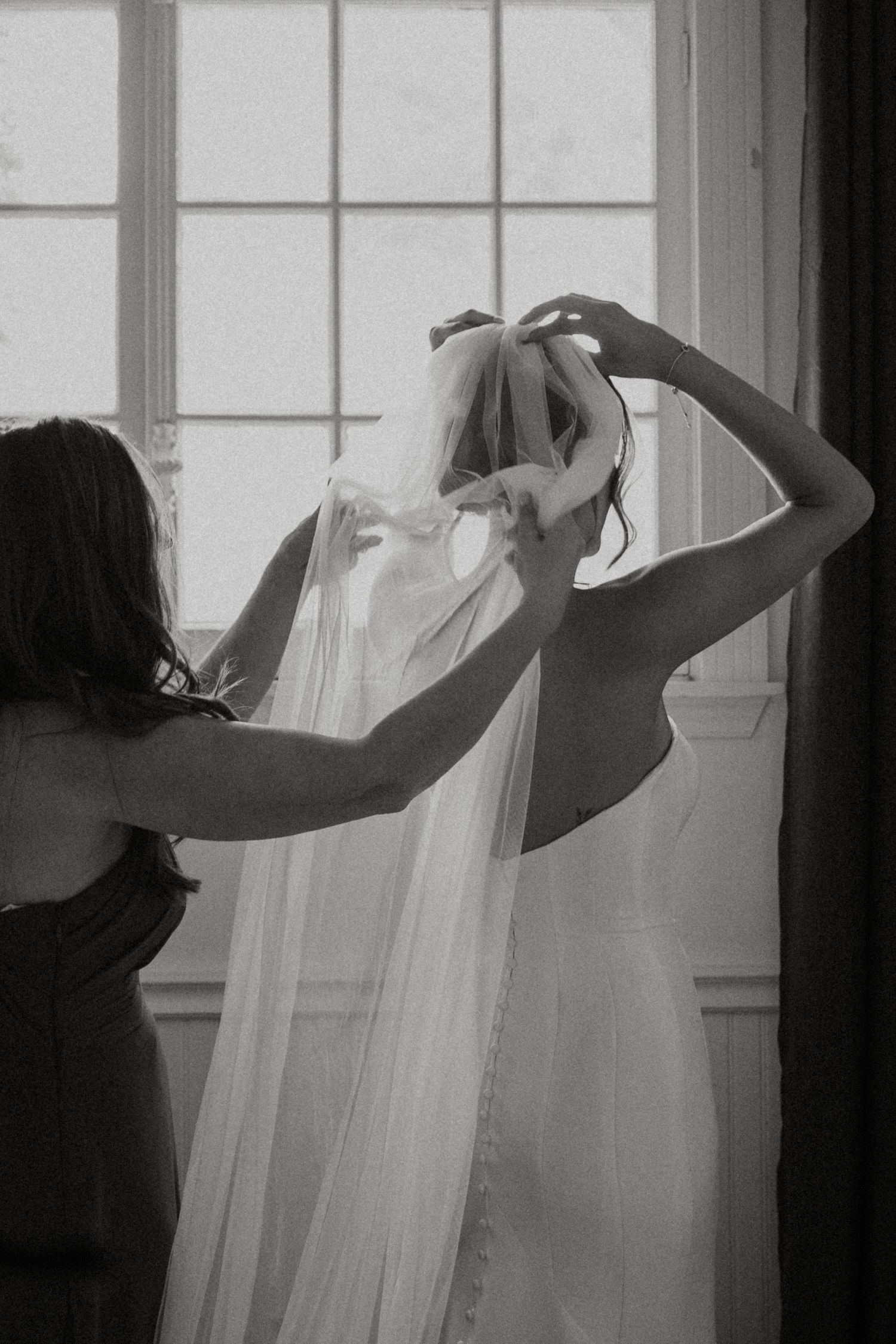 Silhouette of someone adjusting a wedding dress near a window.