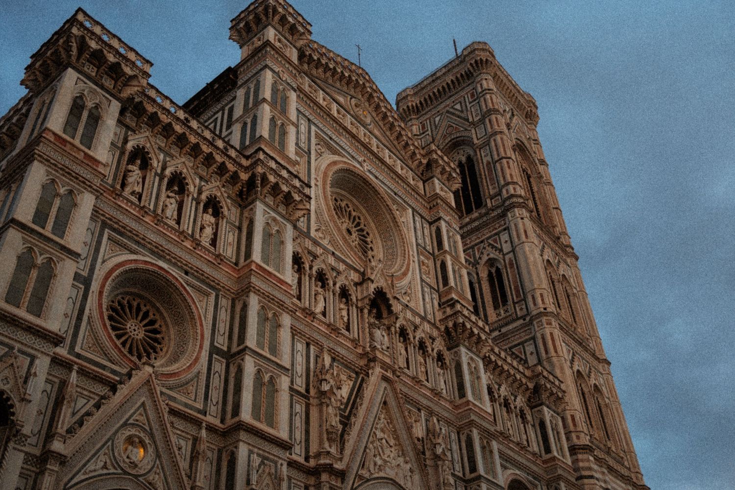 Ornate Gothic architecture of the Florence Cathedral towers against a blue sky in Italy.