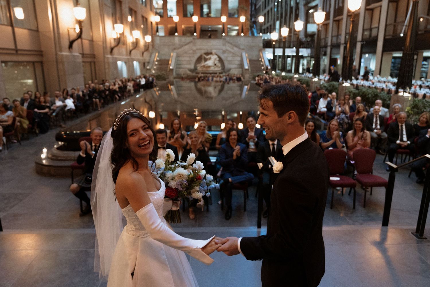 A couple shares their first dance in a grand ballroom during an elegant wedding reception celebration.