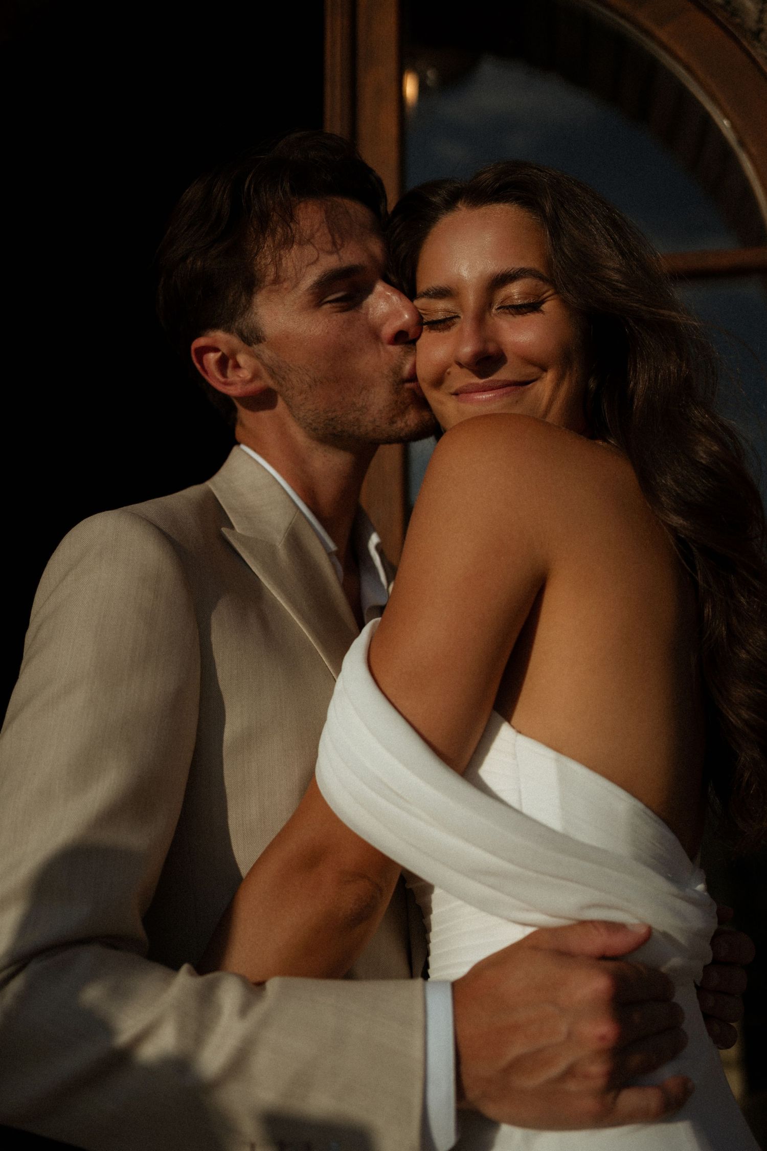 A romantic sequence of wedding photos shows a couple sharing intimate kisses in a dimly lit setting.