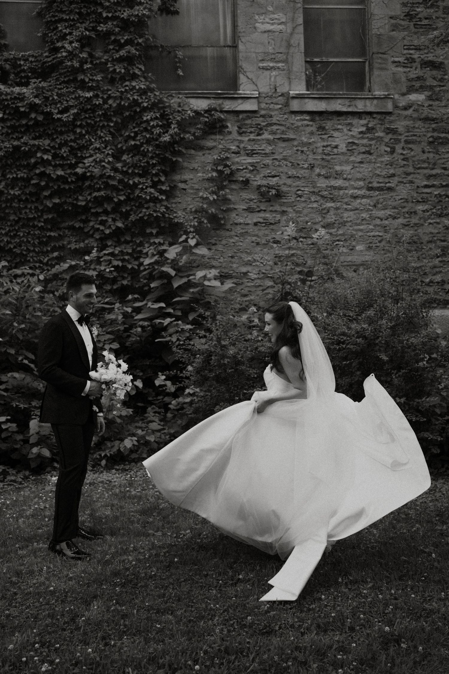 Black and white wedding photos showing movement of bride's dress in garden setting.