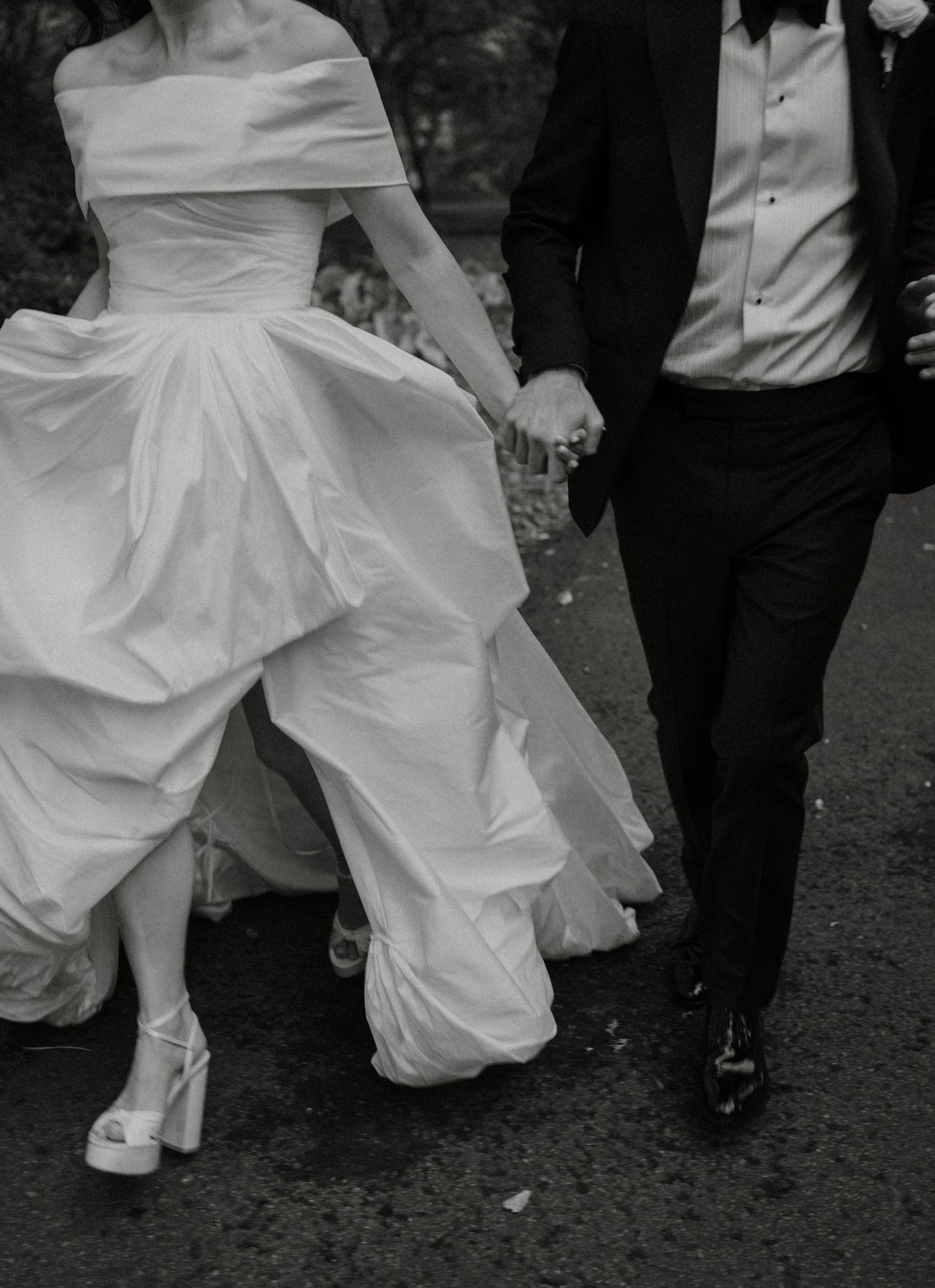 Black and white wedding photos showing close-up details of bride's white dress and groom's dark suit while dancing.