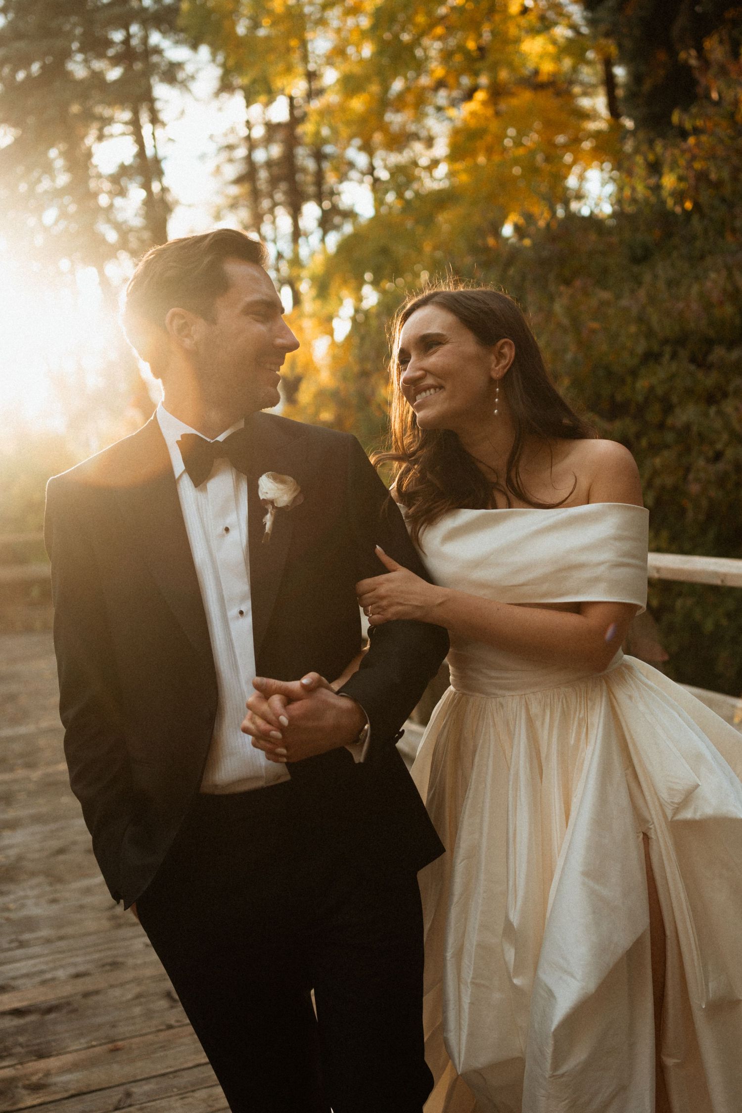 Newlywed couple dances together during golden hour sunset in an outdoor setting.