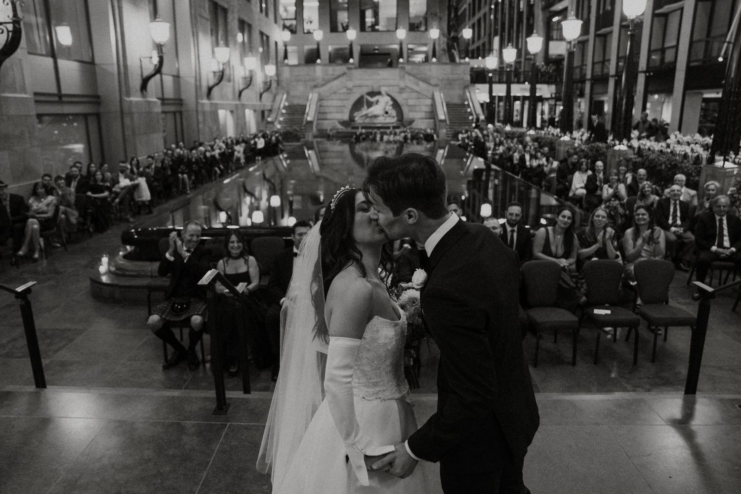 Wedding guests dance together during a reception celebration in a dimly lit ballroom.