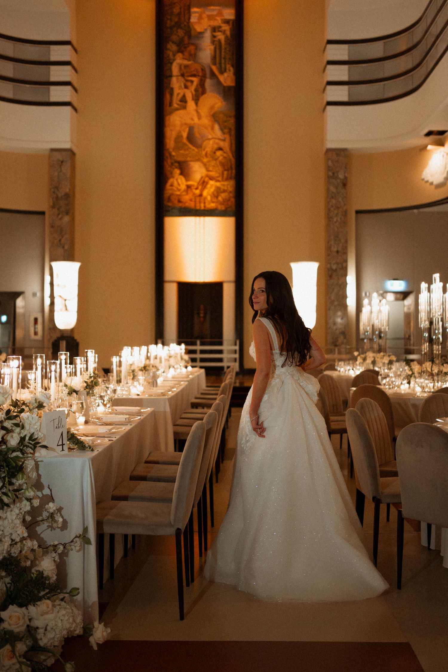 Elegant wedding reception venue with white table settings, candlelight, and romantic lighting in a classic ballroom setting.