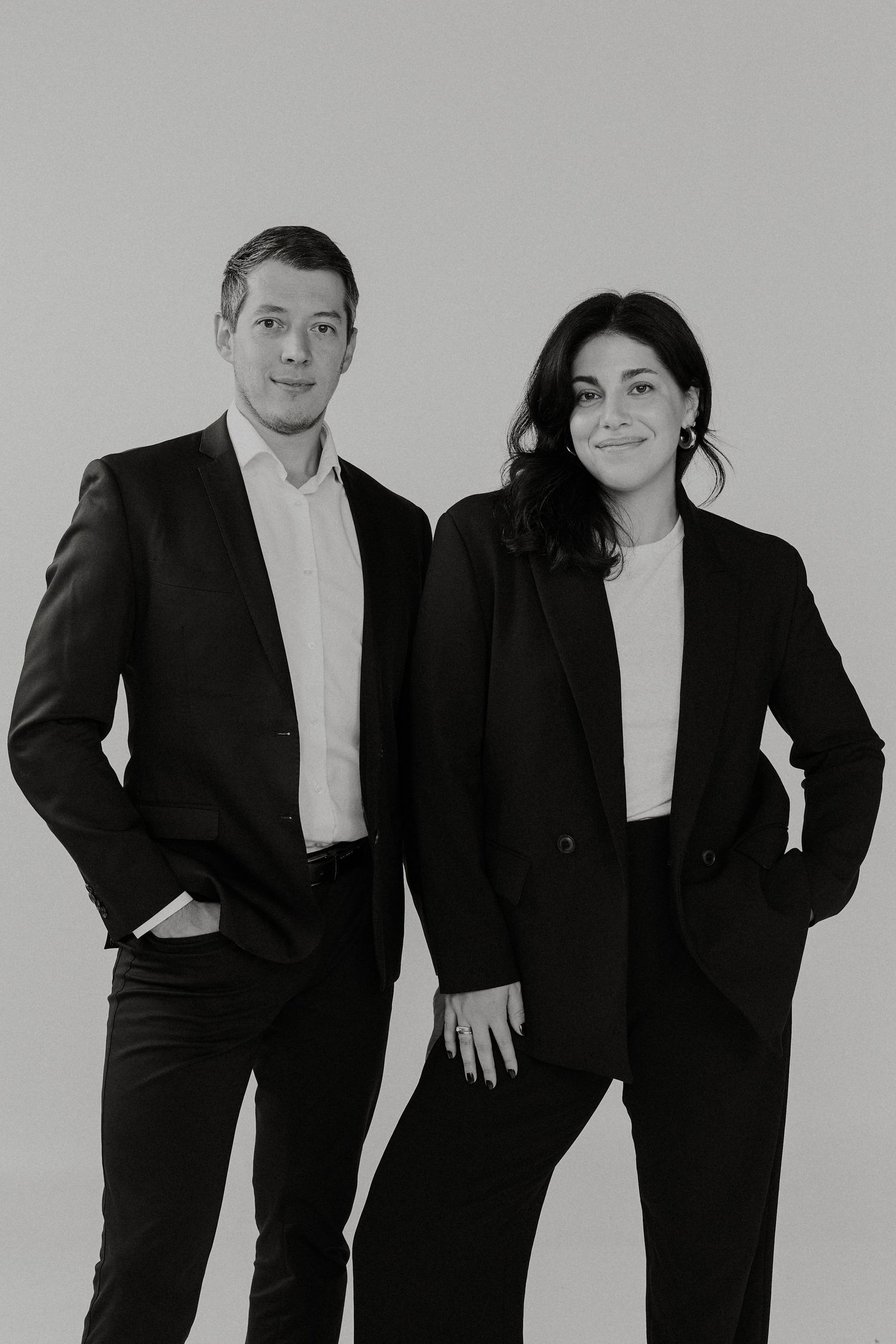 Artistic black and white portrait session with formal attire against grey background.