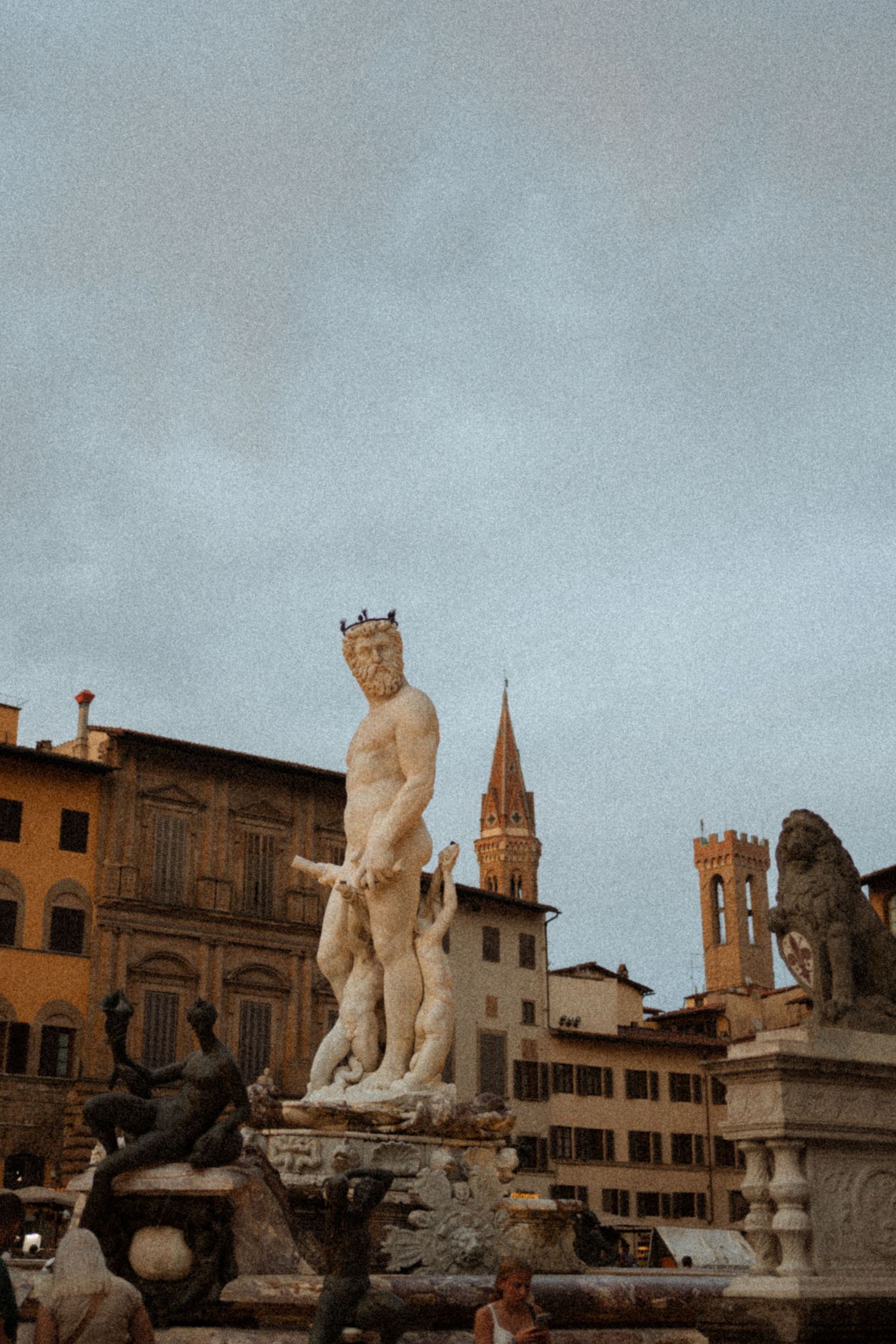 Fountain of Neptune marble statue in Piazza della Signoria, Florence, Italy, with historic buildings and towers in background.