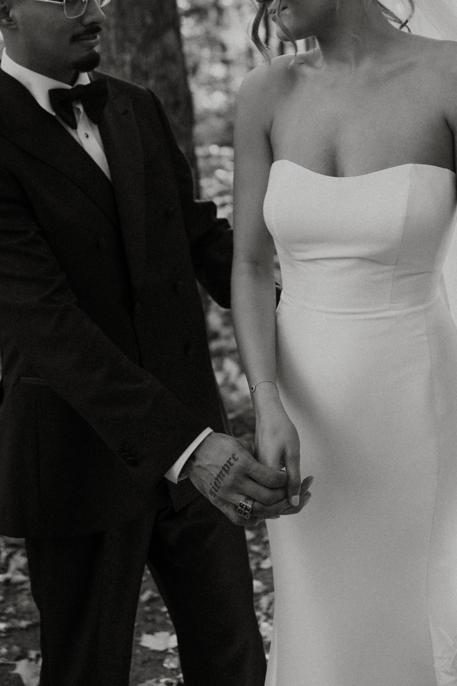 Black and white wedding photo showing couple in elegant attire standing close together during intimate moment.