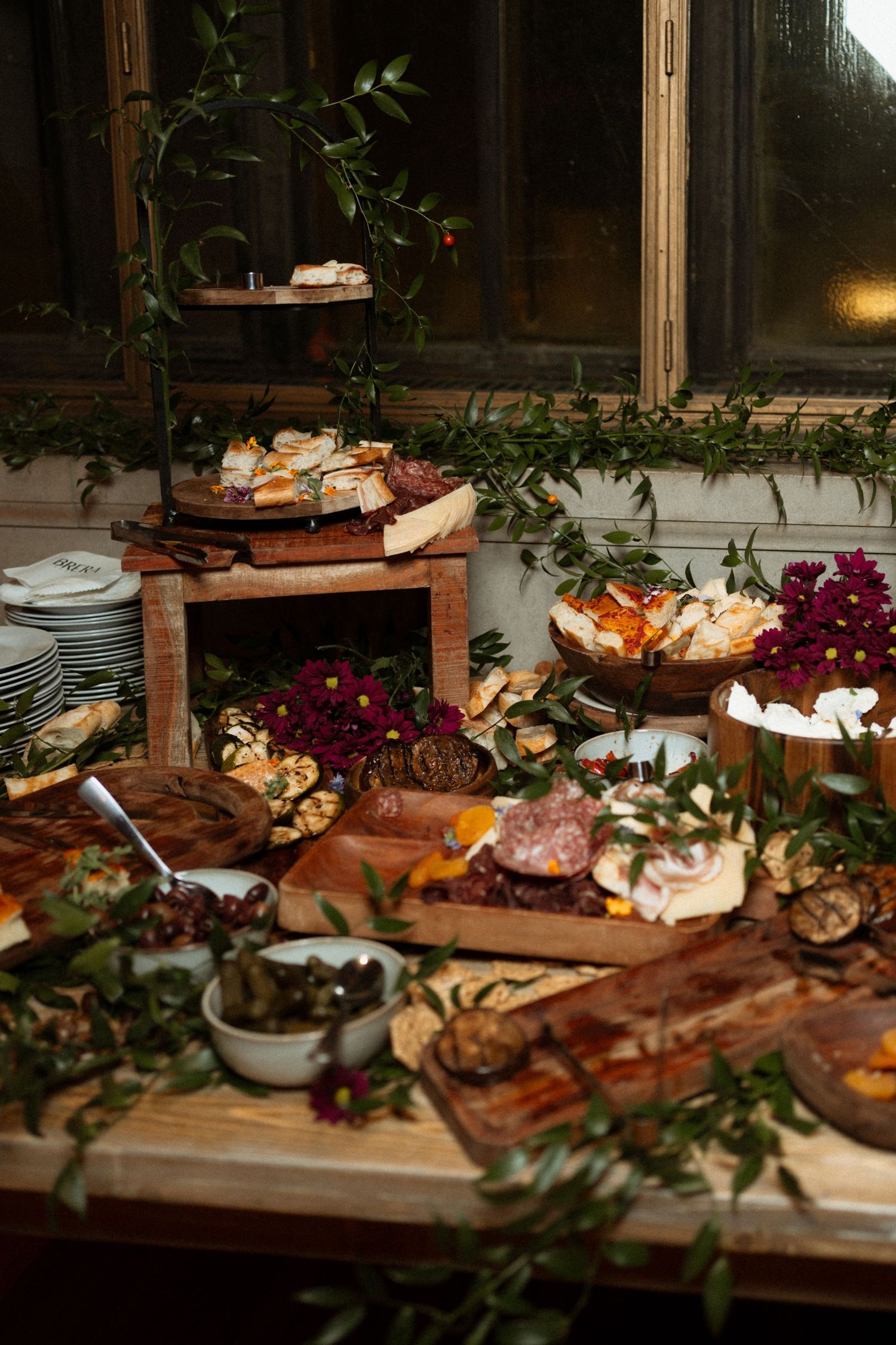 Elegant charcuterie spread with meats, cheeses, crackers, and fresh flowers on rustic wooden boards for an event.