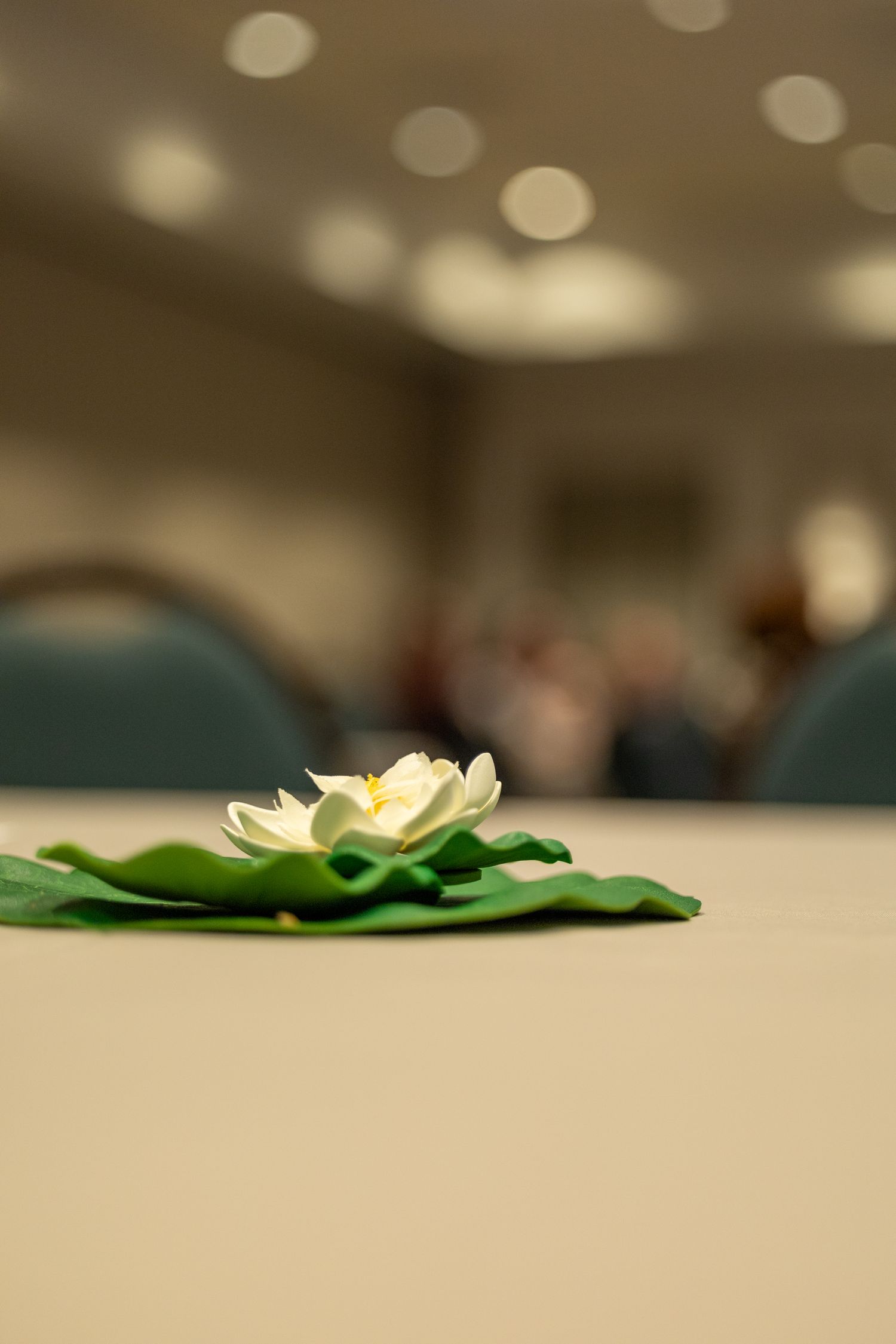 Close-up of a white lotus flower decoration on a green leaf centerpiece at a conference table.