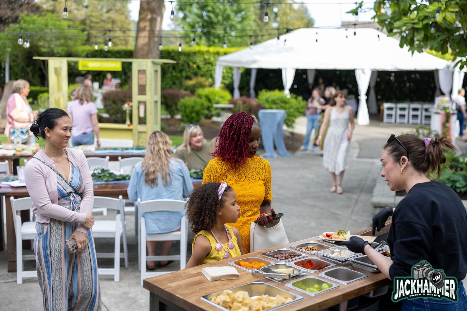 People gathered at an outdoor food buffet table at a Jackhammer catered event.