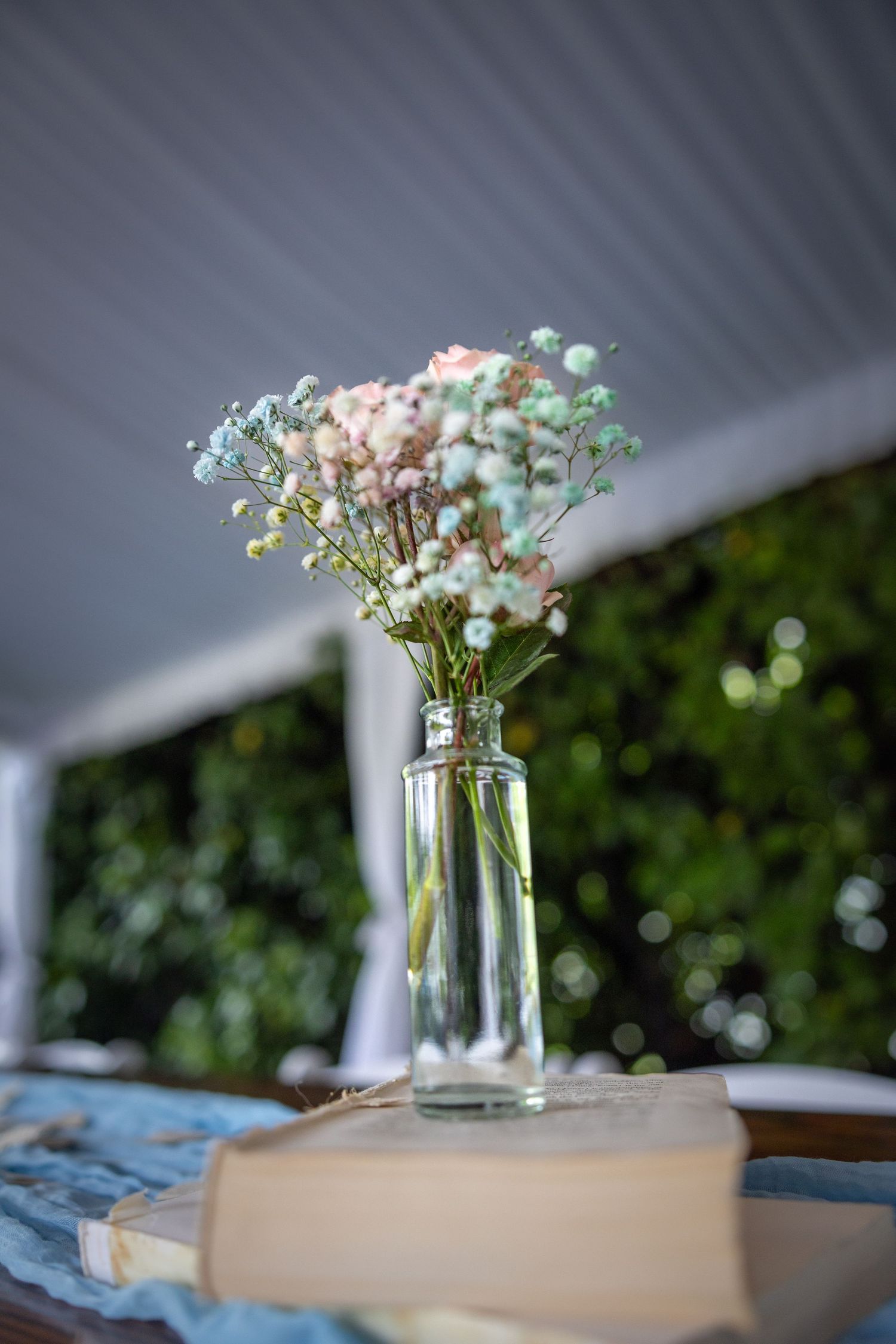 Small glass vase with pink and white baby's breath flowers sitting on a vintage book.