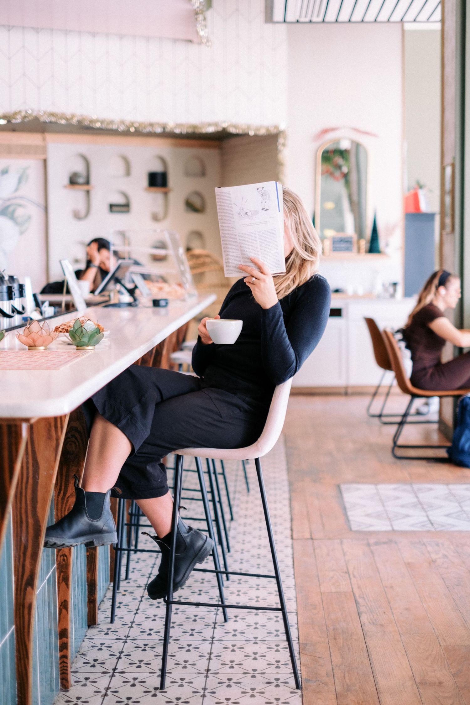 People relaxing at a modern cafe bar with wooden floors and patterned tiles.