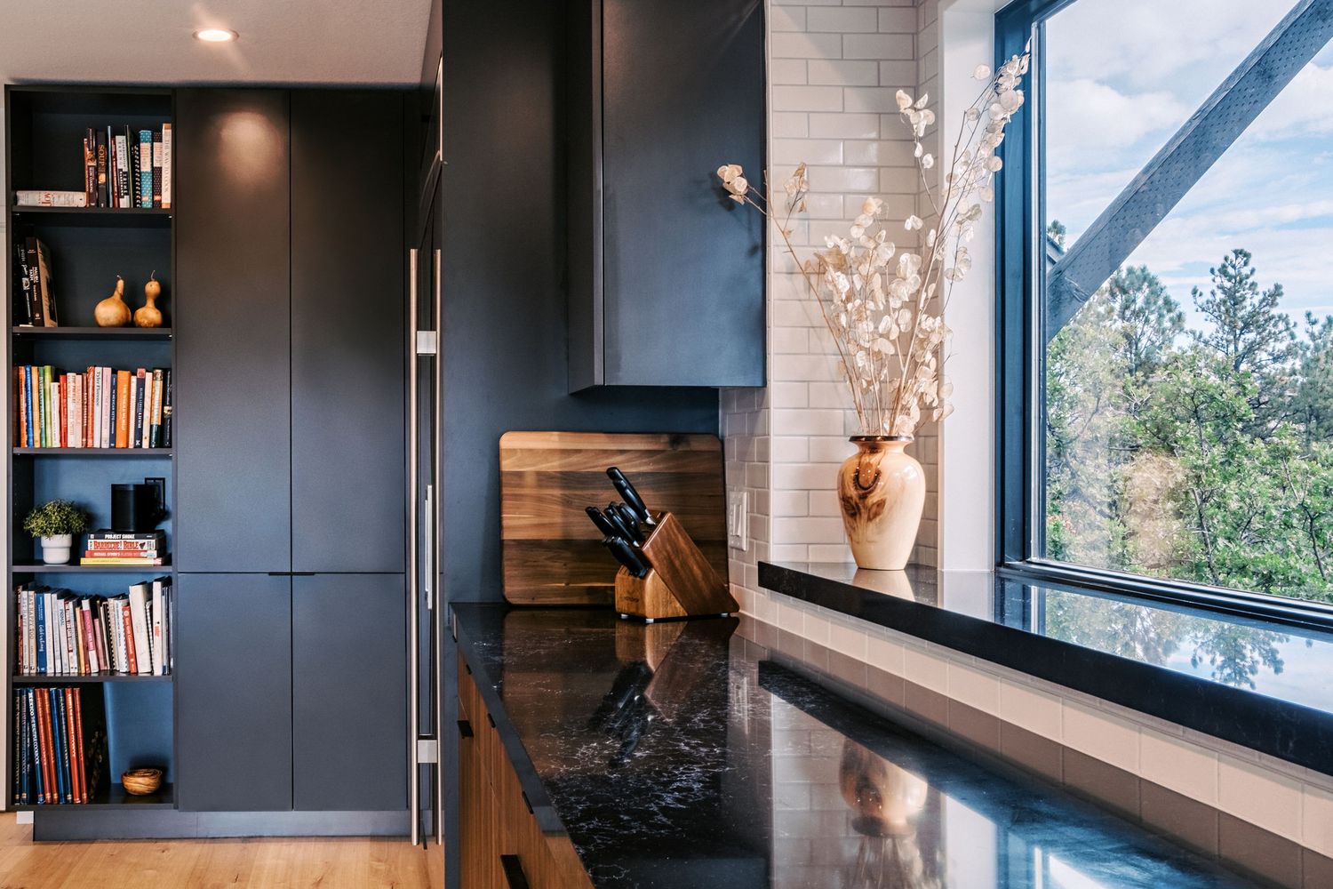 Modern home library with dark wood shelving, built-in cabinets, and large windows offering natural light.