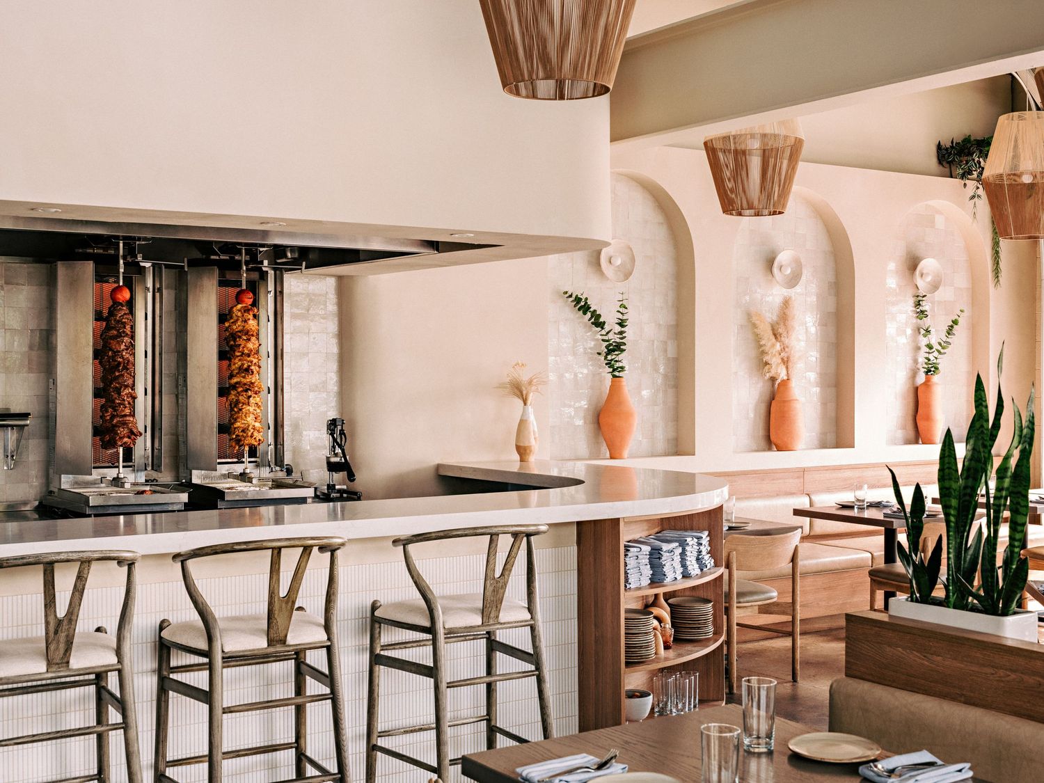 Modern restaurant interior with white walls, wooden furniture, and hanging pendant lights creating a bright, airy atmosphere.