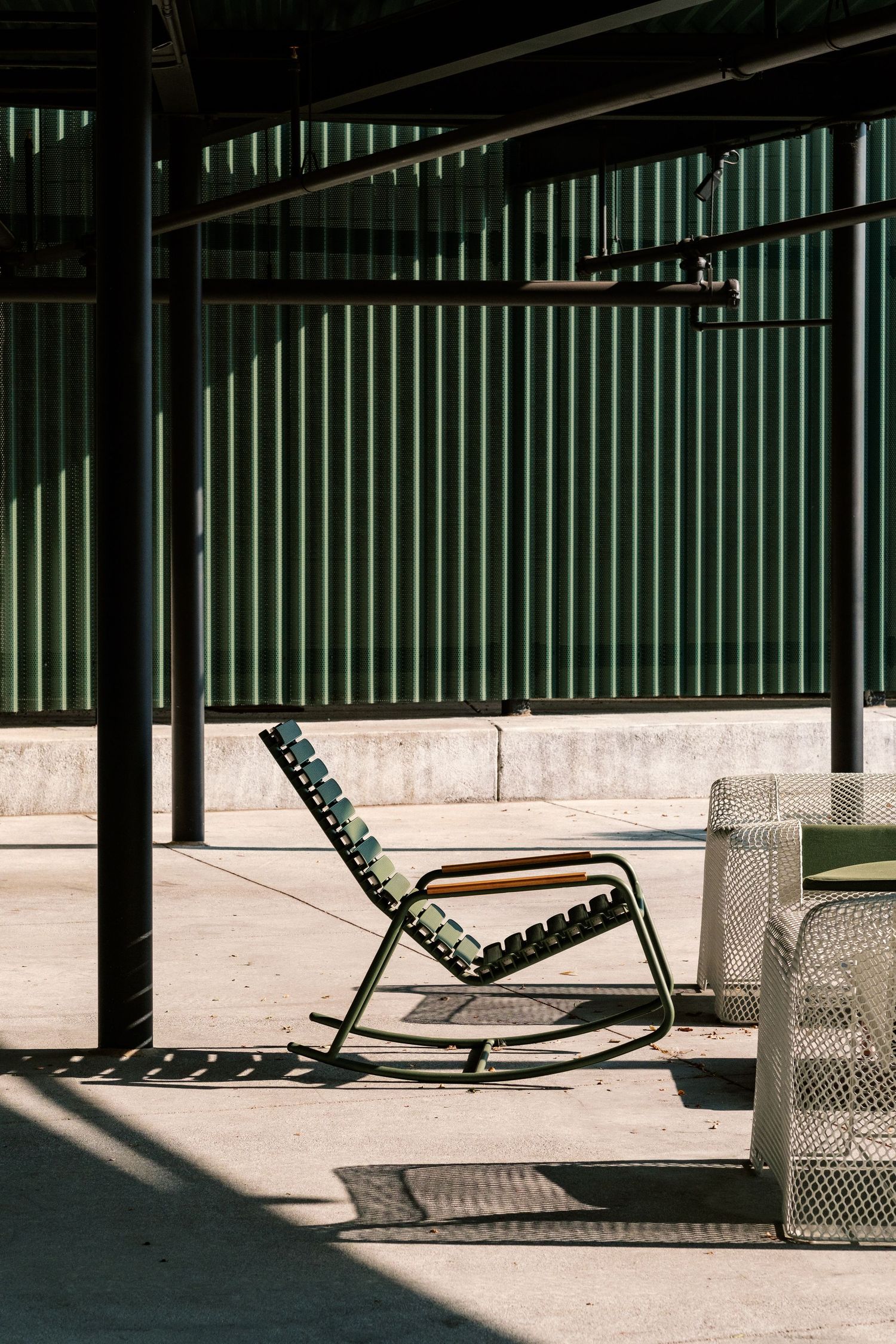 Modern outdoor seating area with sleek metal lounge chairs arranged under a covered patio space.
