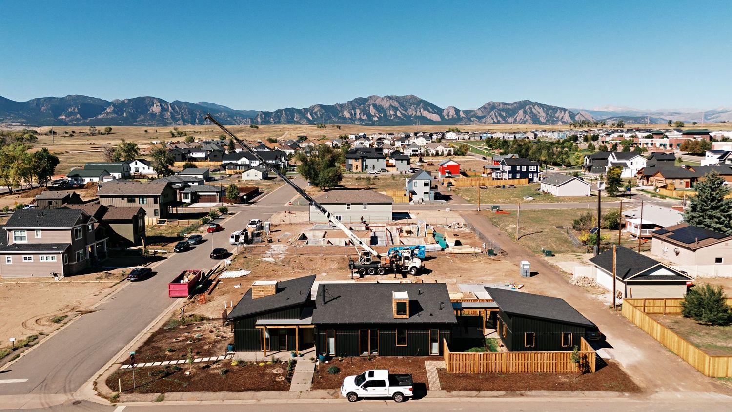 Aerial panorama of residential neighborhood with mountain range visible in the background.