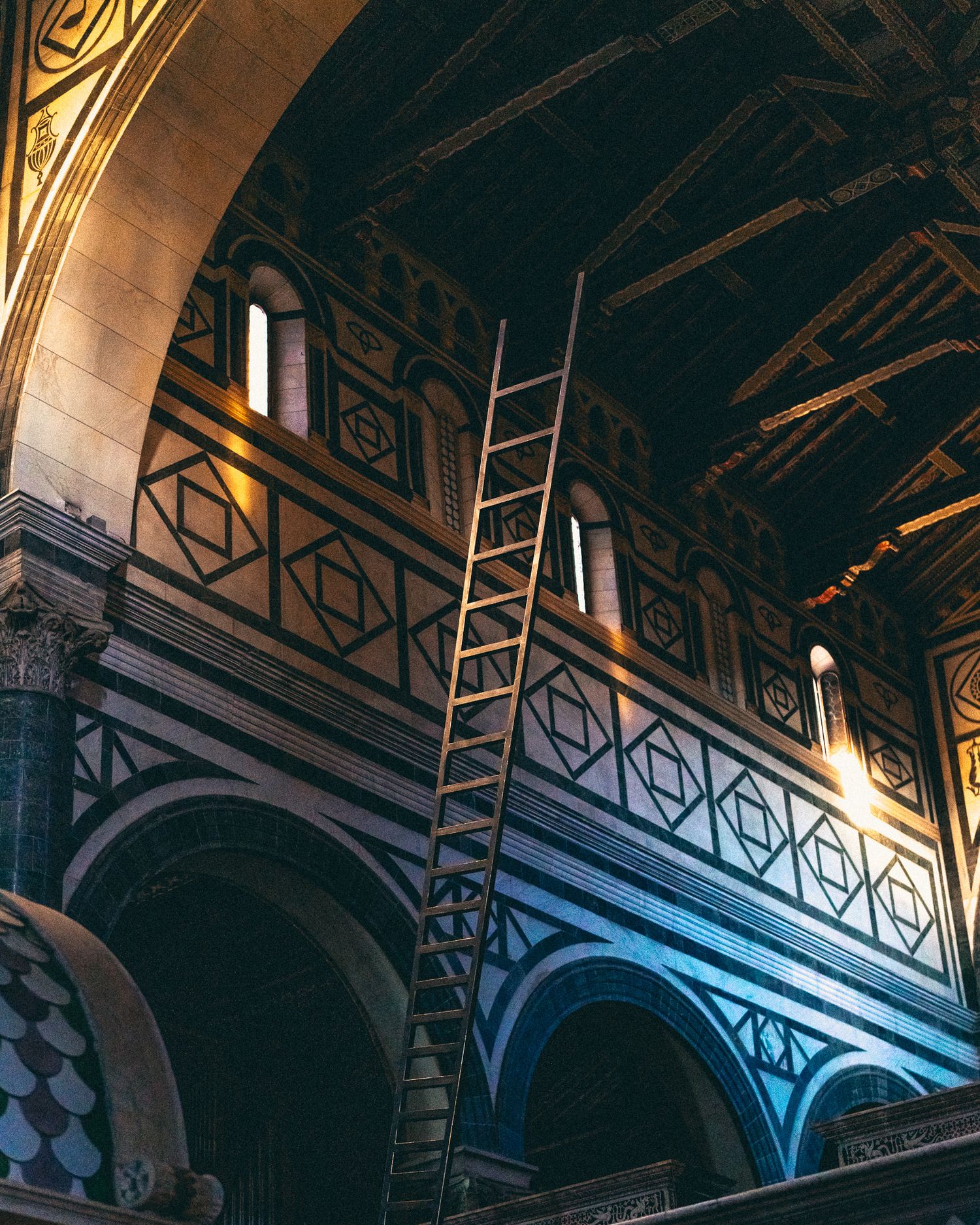 Architectural detail showing ornate arches and geometric patterns in a dimly lit historic interior space.