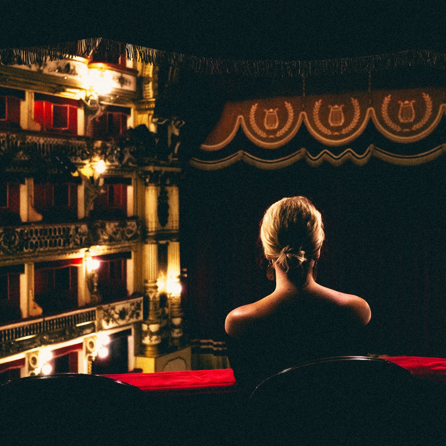 Dark theater interior with red pool tables and dramatic lighting creating a moody billiards atmosphere.