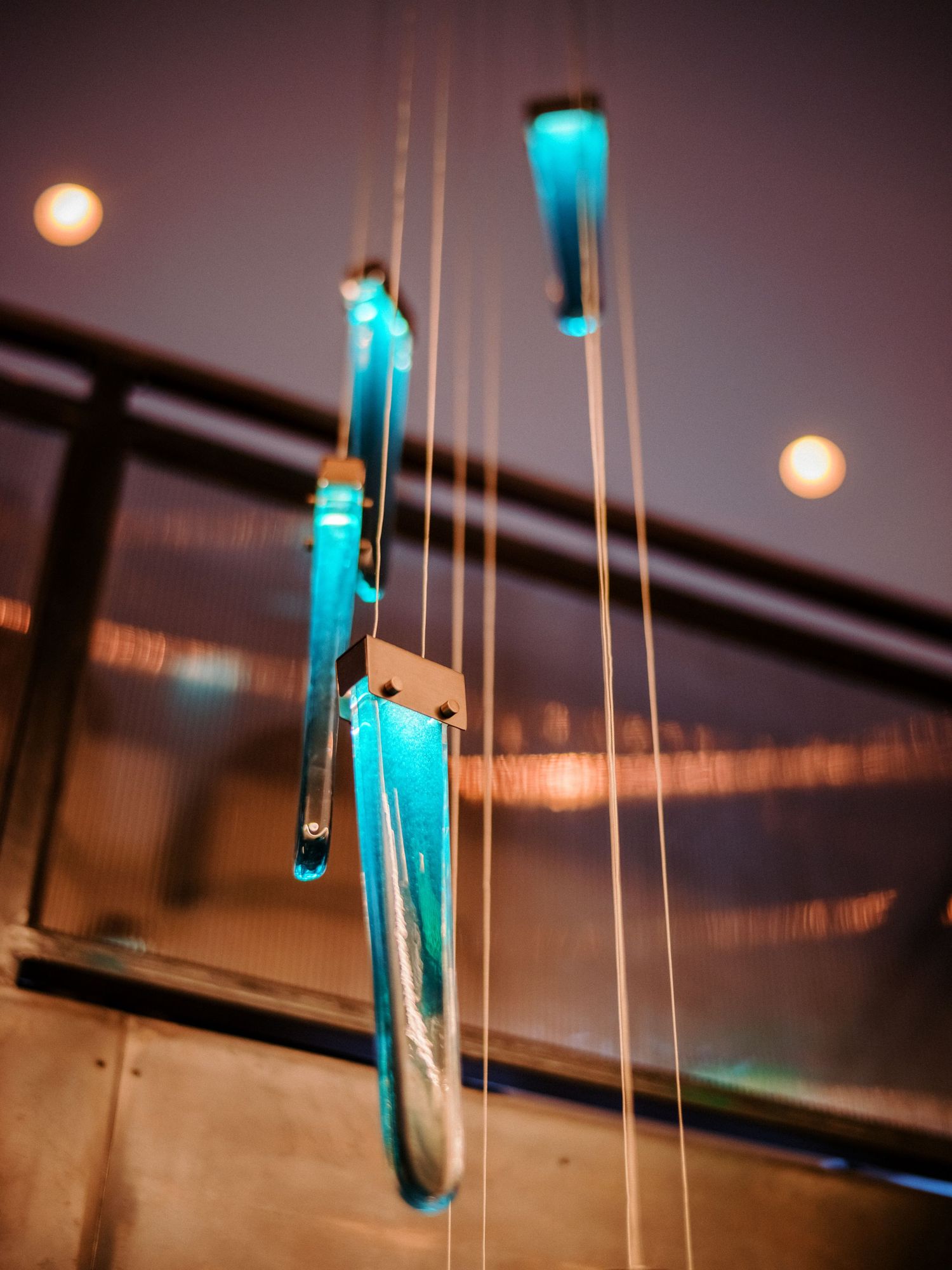 Hanging blue glass pendant lights create modern ambiance against a dark ceiling.
