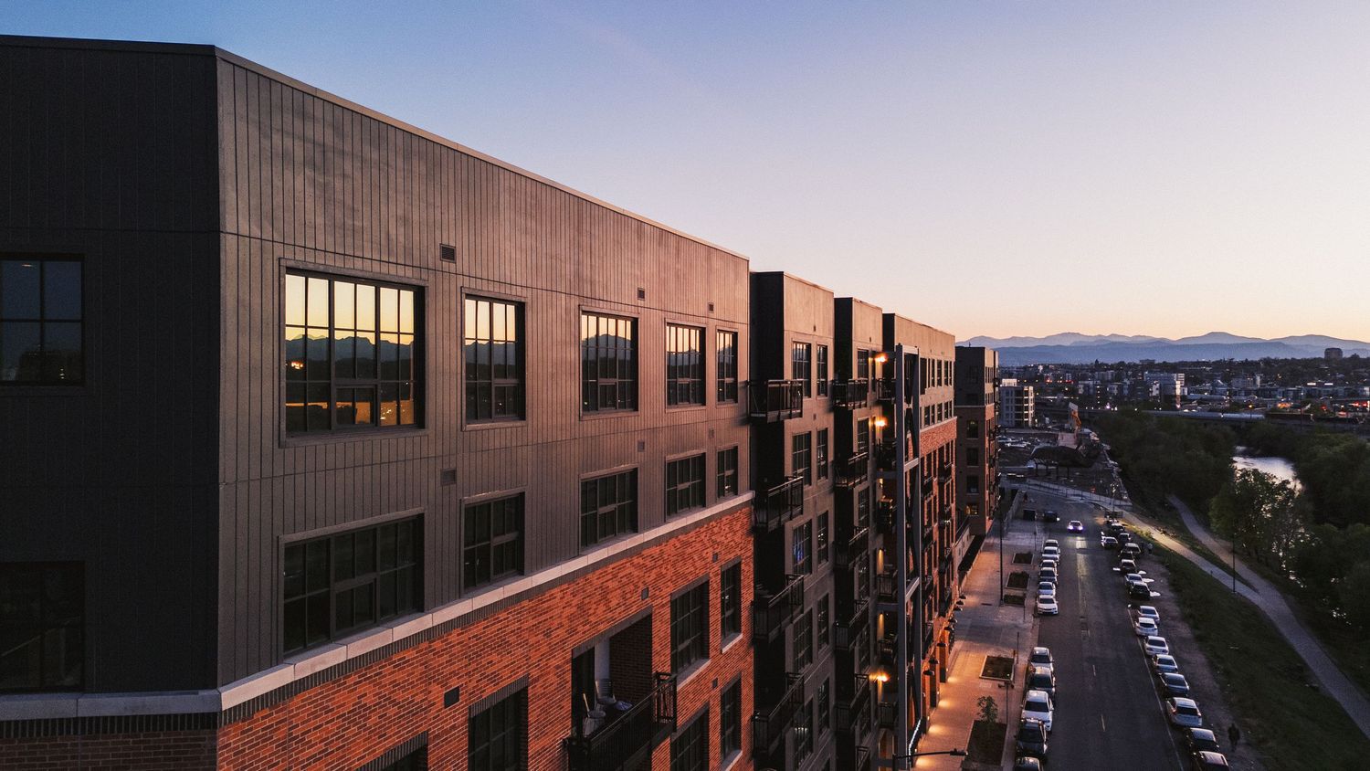 Dusk panorama of city buildings with illuminated windows stretching along the horizon.