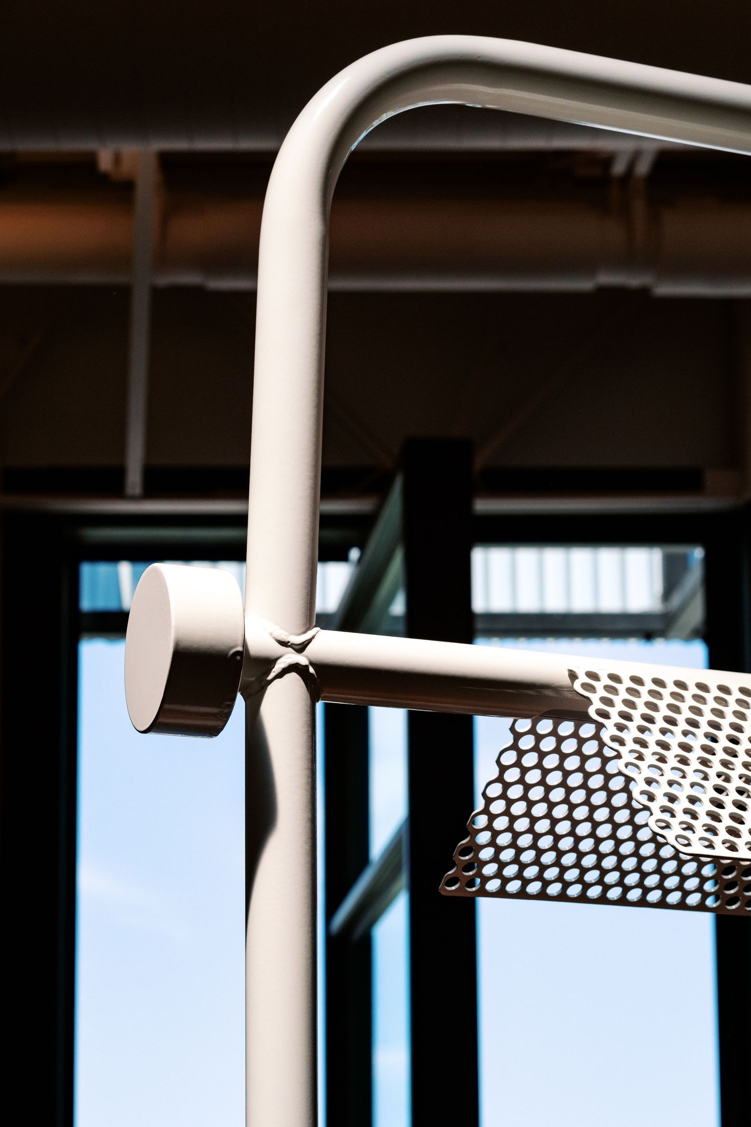 Modern white metal handrail detail showing geometric patterns and clean lines against a dark background.