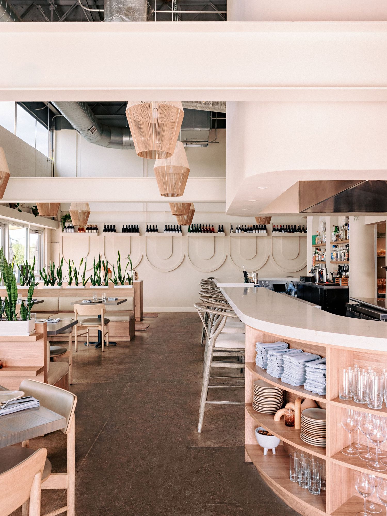 Restaurant service station with stacked plates, glassware, and wooden storage solutions in an open layout.