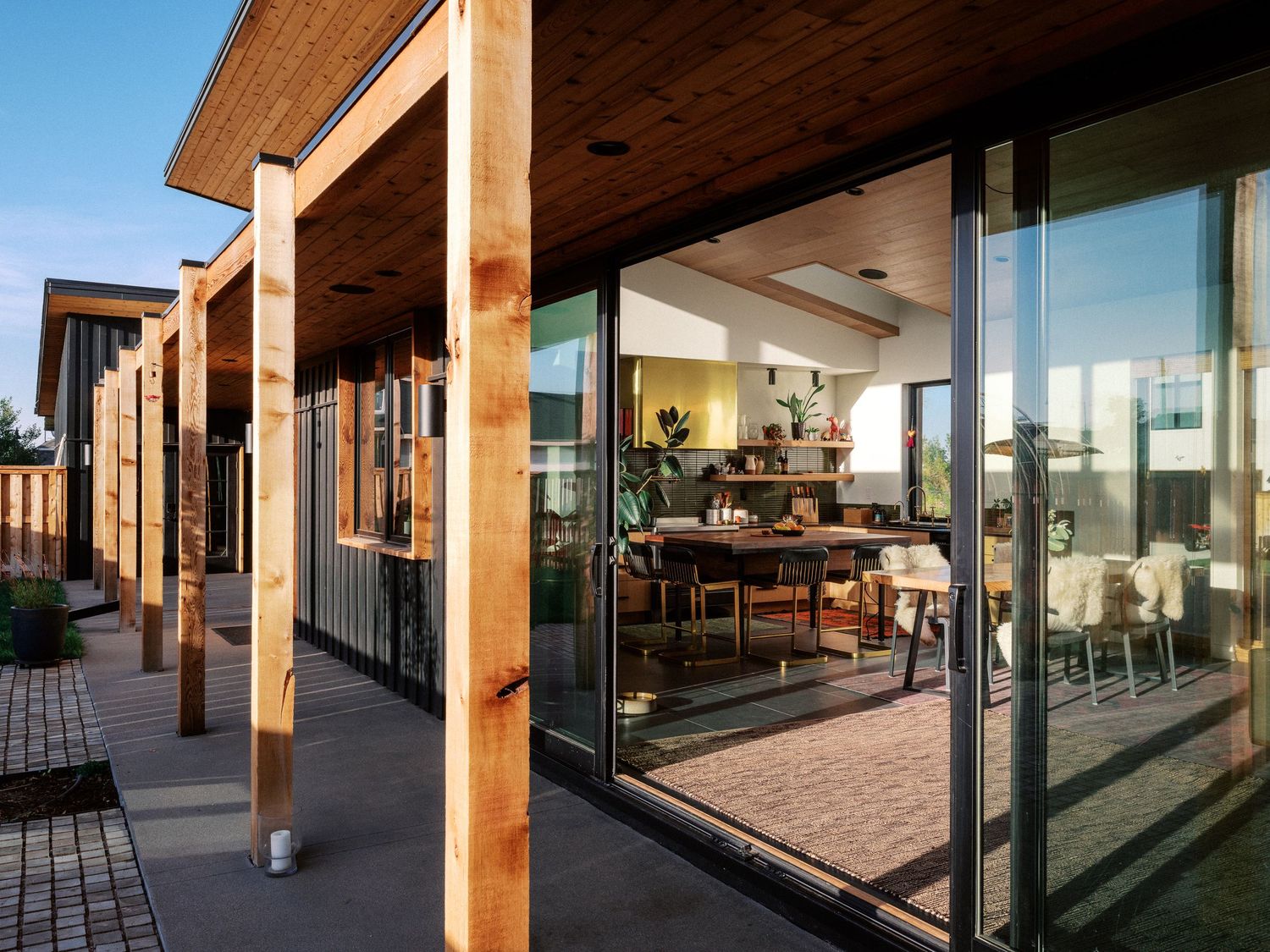 Contemporary building exterior featuring wooden posts and large glass windows with covered patio area.