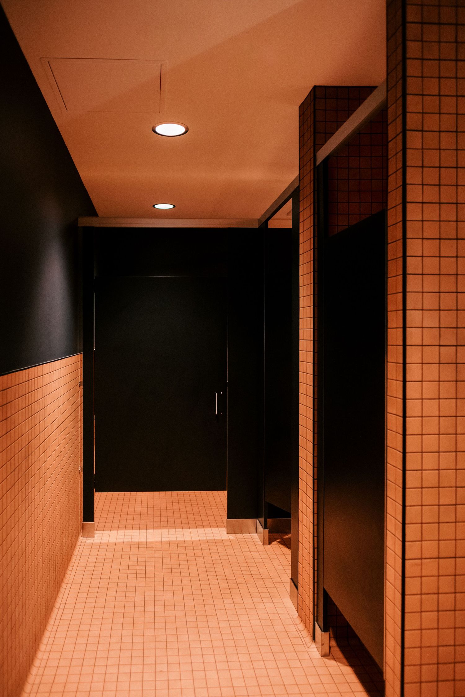Modern tiled hallway with recessed lighting creating dramatic shadows and geometric patterns.